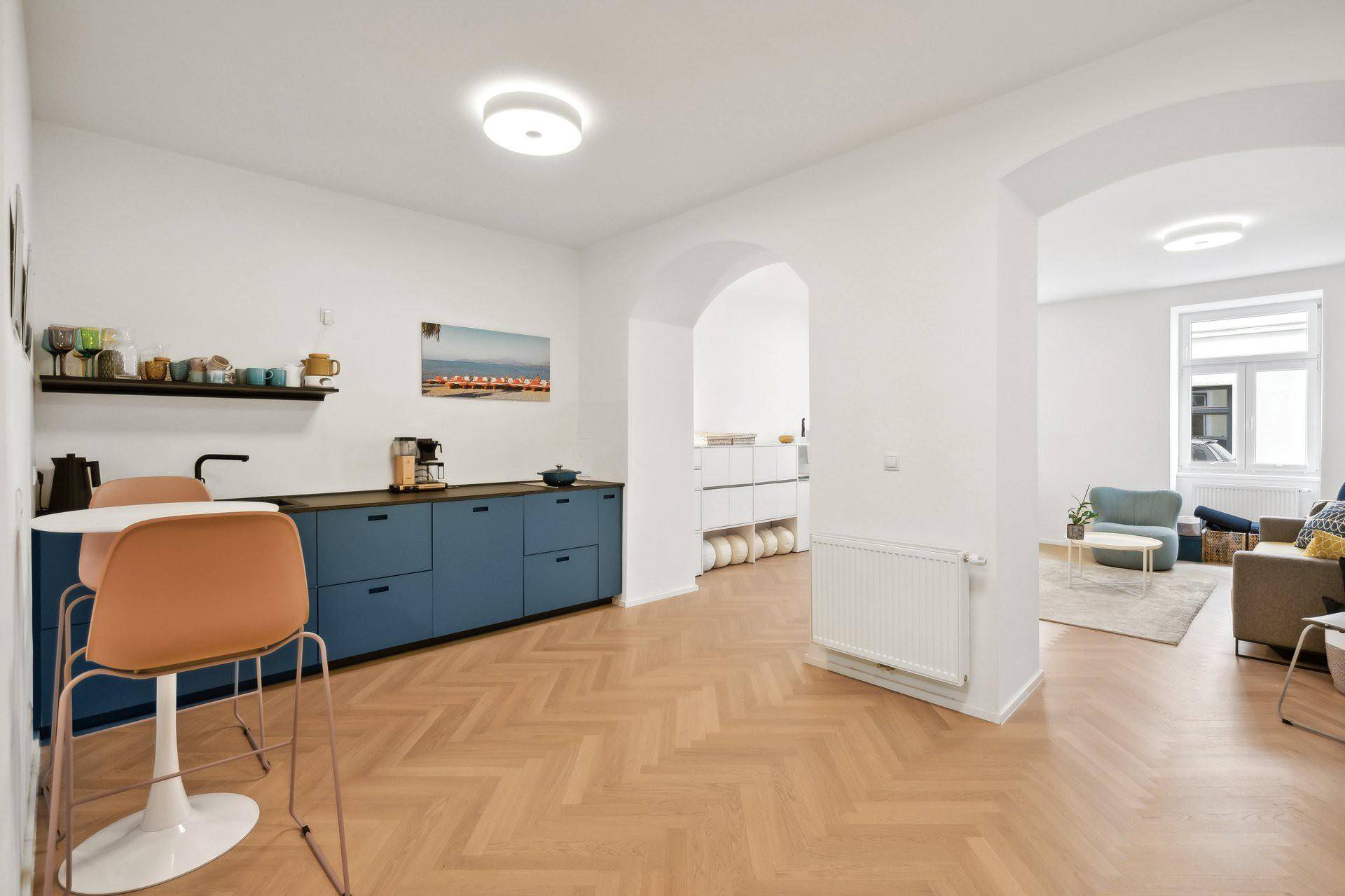 Moderne Küche mit blauen Unterschränken, Frühstücksbar und offenem Zugang zum Wohnbereich.