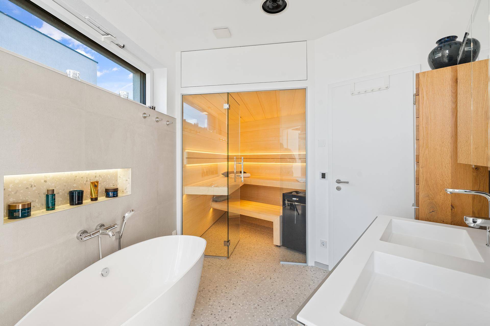 Luxuriöses Badezimmer mit integrierter Sauna, freistehender Badewanne und Doppelwaschbecken.