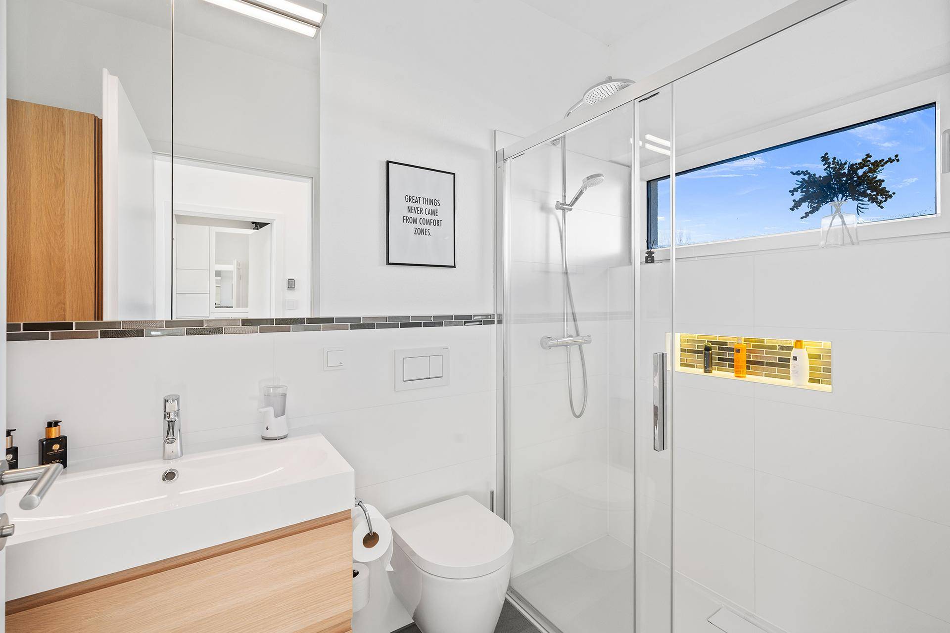 Modernes Badezimmer mit Dusche, wandhängendem WC und Fenster für Tageslicht.