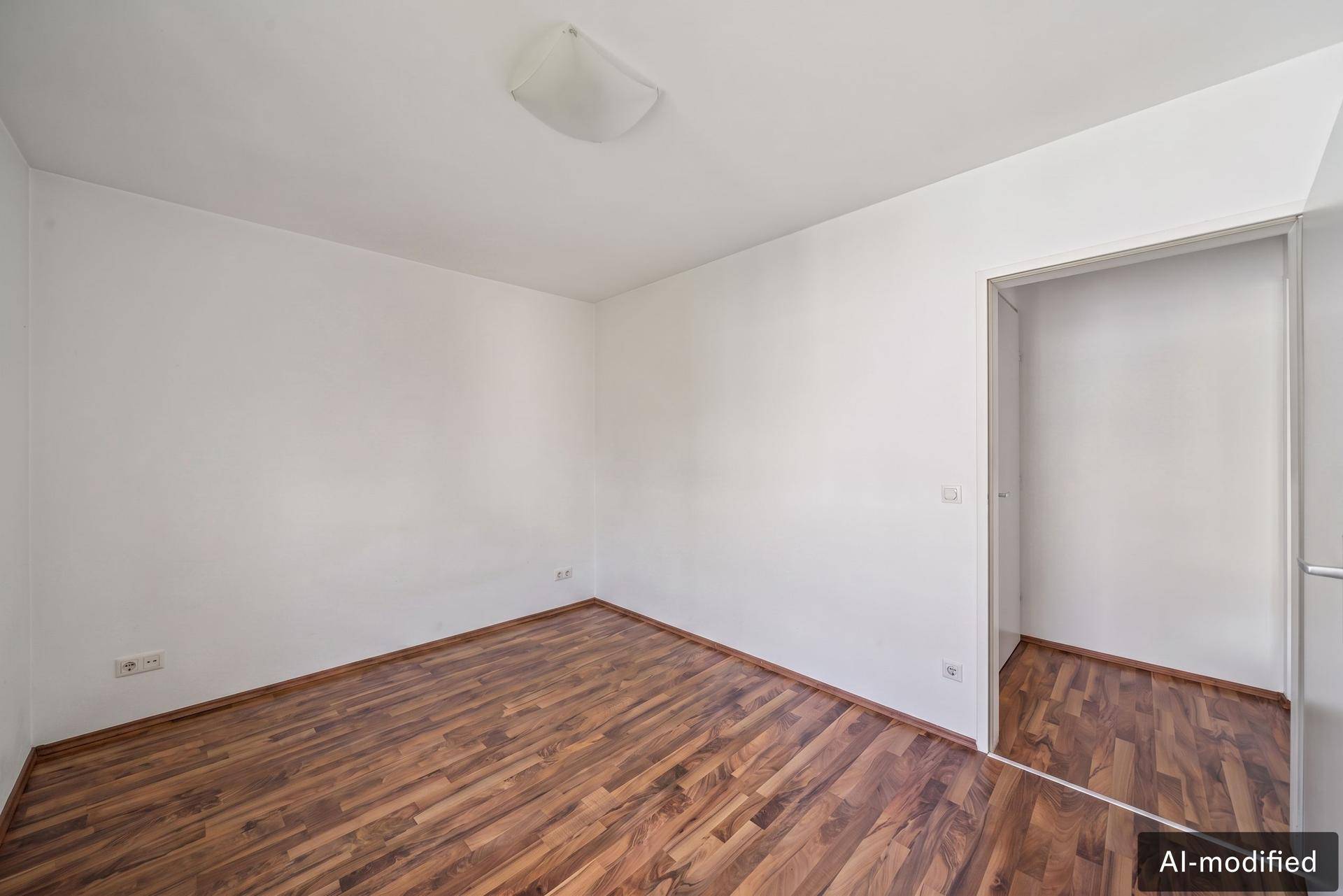 Leeres Zimmer mit Holzboden und weißen Wänden, bereit zur individuellen Gestaltung.