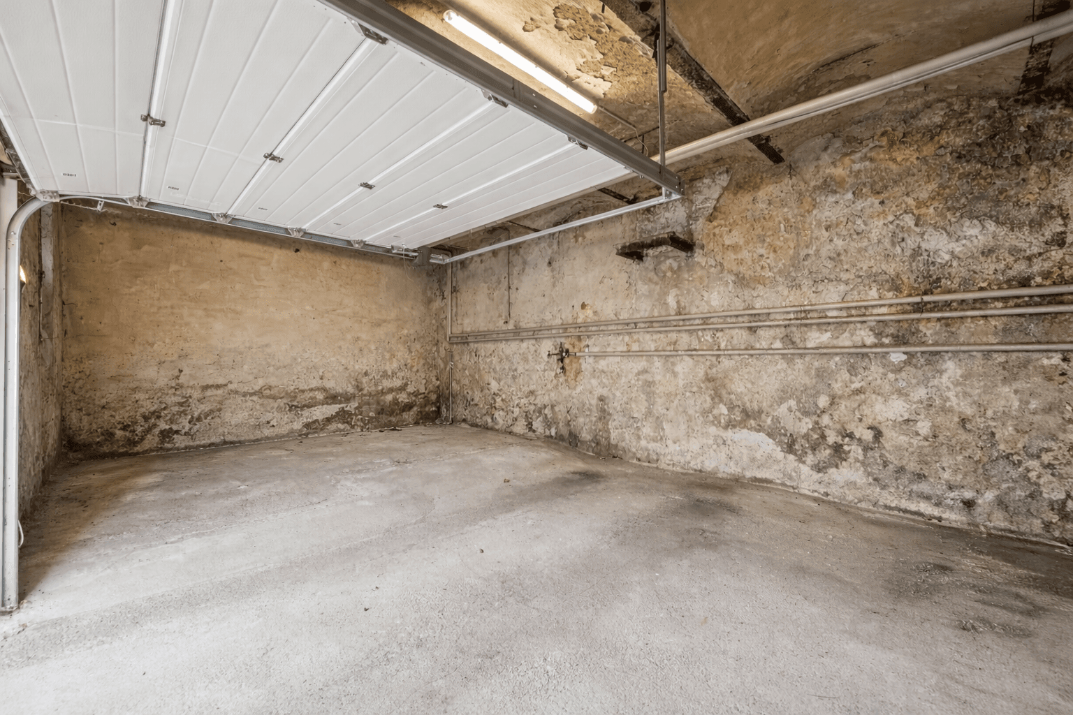 Leere Garage mit Betonboden und rauen Wänden, bereit zur Nutzung.