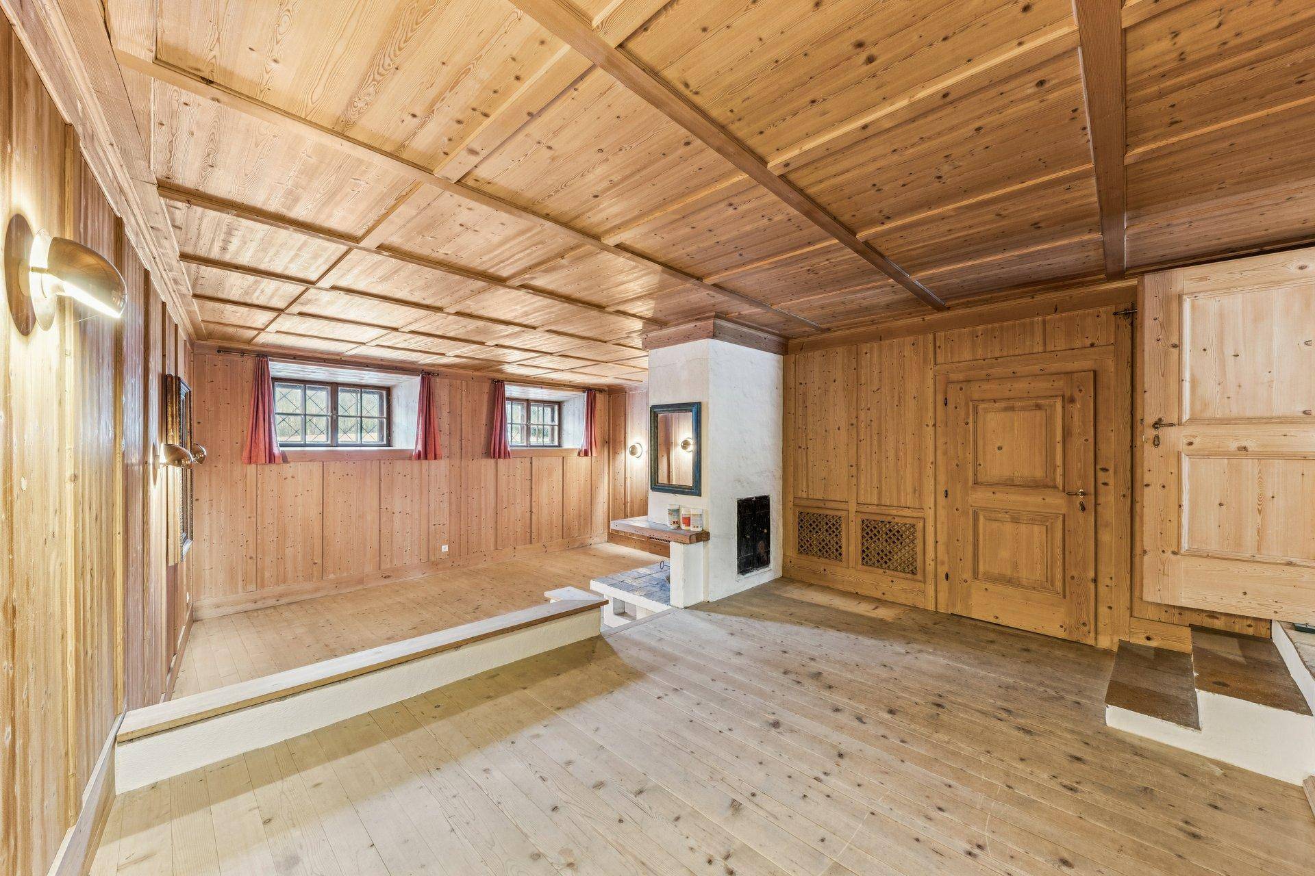 Gemütlicher Raum mit Holztäfelung an Wänden und Decke, Holzboden und integriertem Kamin.