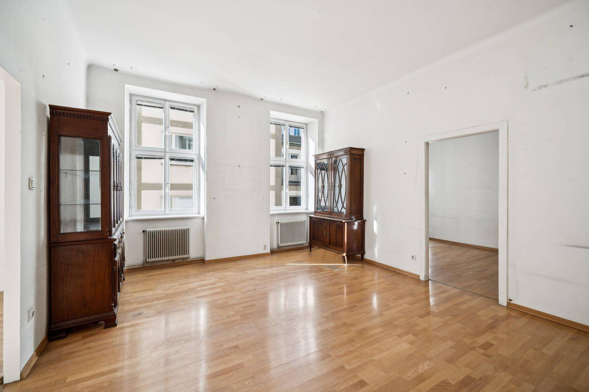 Geräumiges Zimmer mit Parkettboden, hohen Decken und zwei antiken Holzschränken.
