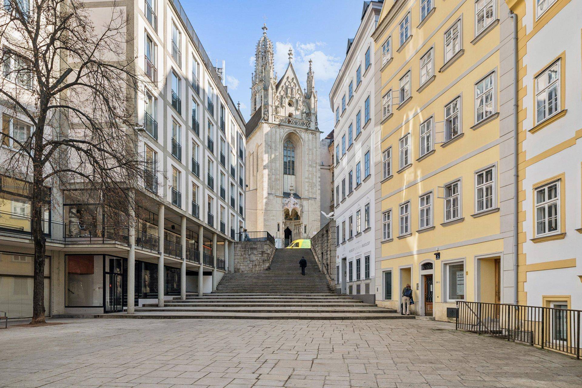 Historische Straße mit Kopfsteinpflaster, die zu einer imposanten Kirche mit Treppen führt.