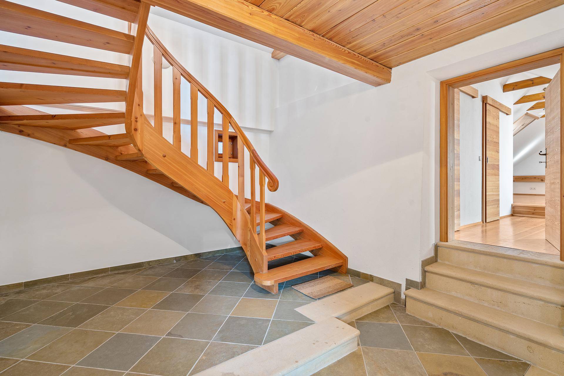 Holztreppe mit Steinfliesenboden und Zugang zu weiteren Räumen im traditionellen Stil.