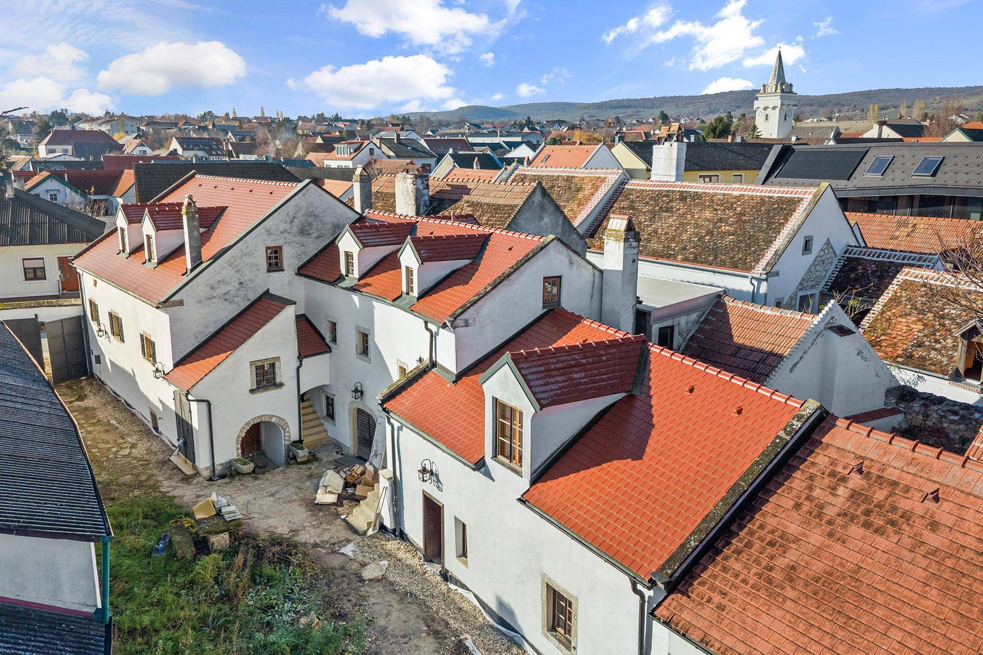 Dachlandschaft eines historischen Gebäudekomplexes mit roten Ziegeldächern und Gauben.