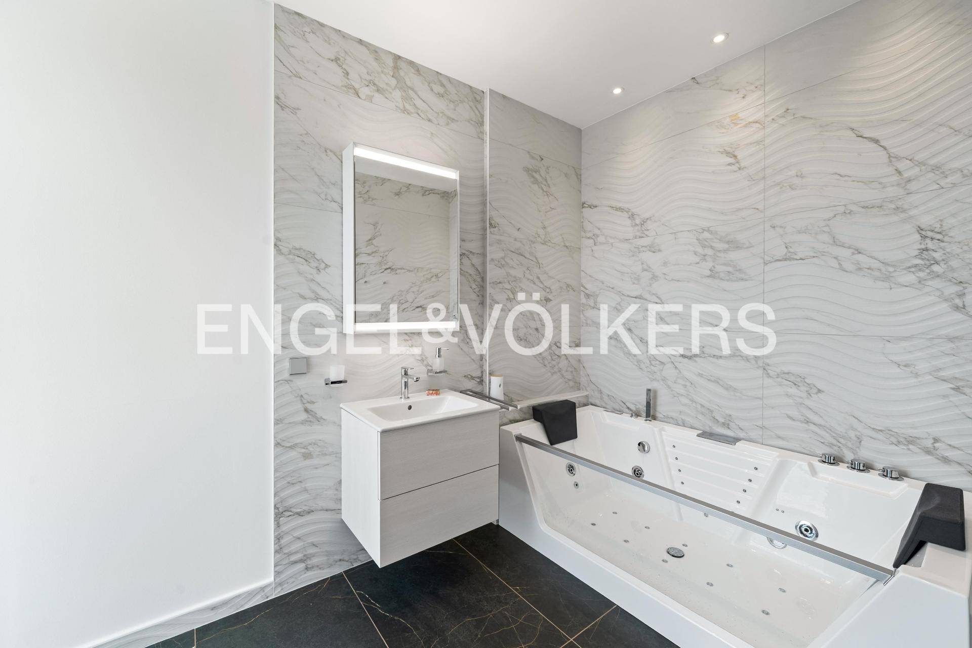 Luxuriöses Badezimmer mit Whirlpool-Badewanne, Marmorfliesen und modernem Waschtisch.