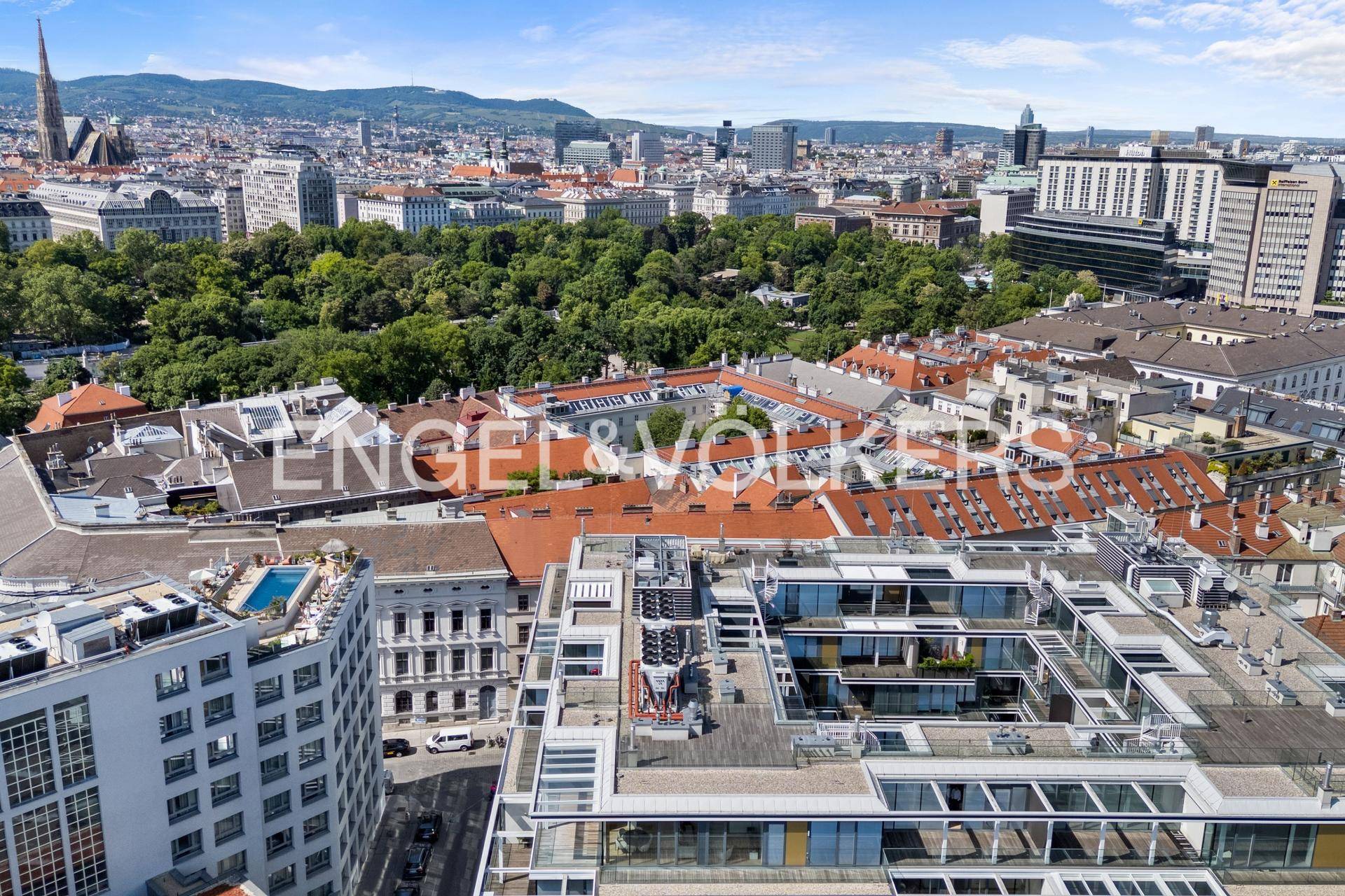 Panoramablick über die Dächer der Stadt Wien mit viel Grün und historischen Gebäuden.