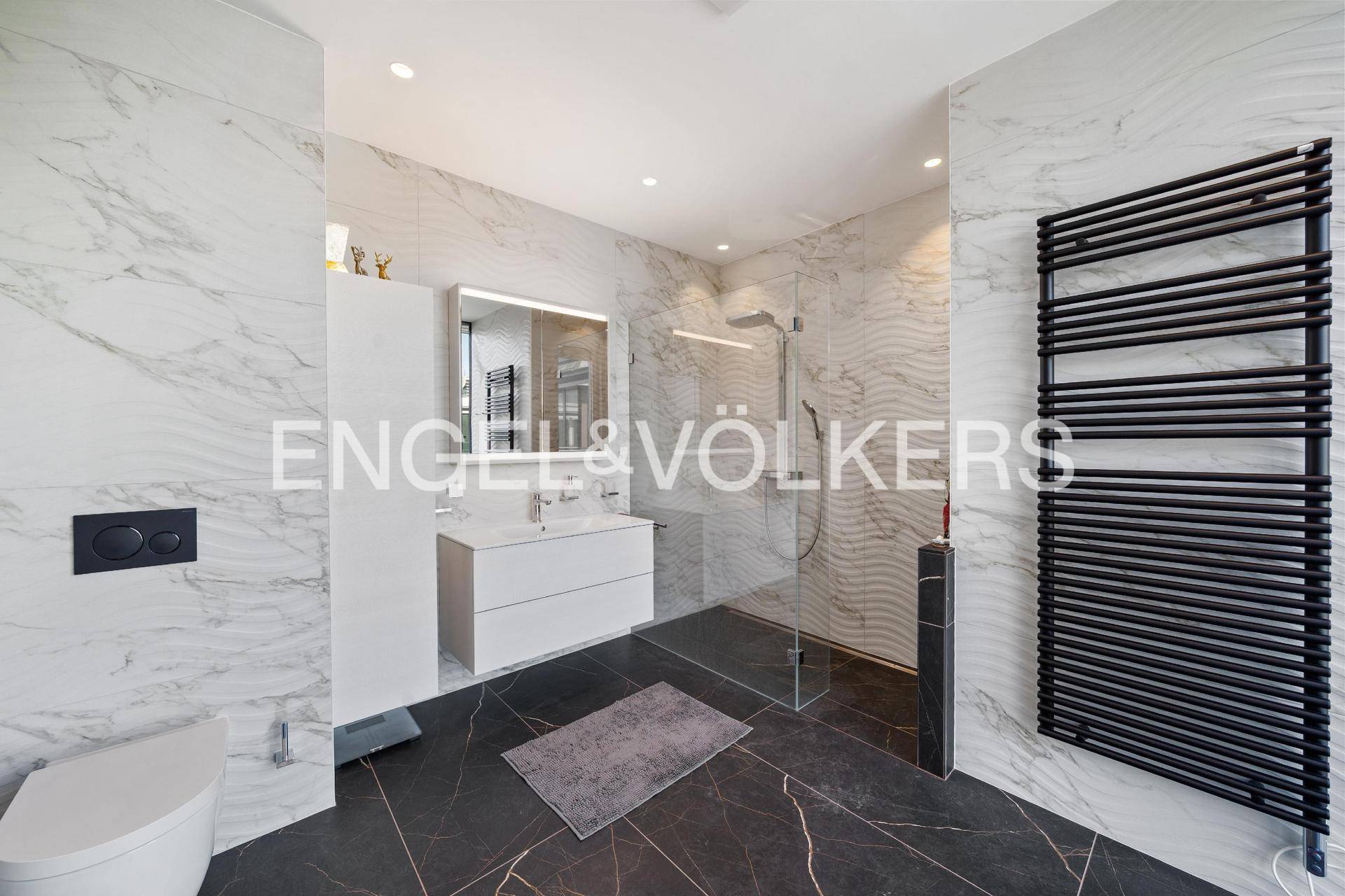 Elegantes Badezimmer mit Marmorfliesen, ebenerdiger Dusche und beheiztem Handtuchhalter.