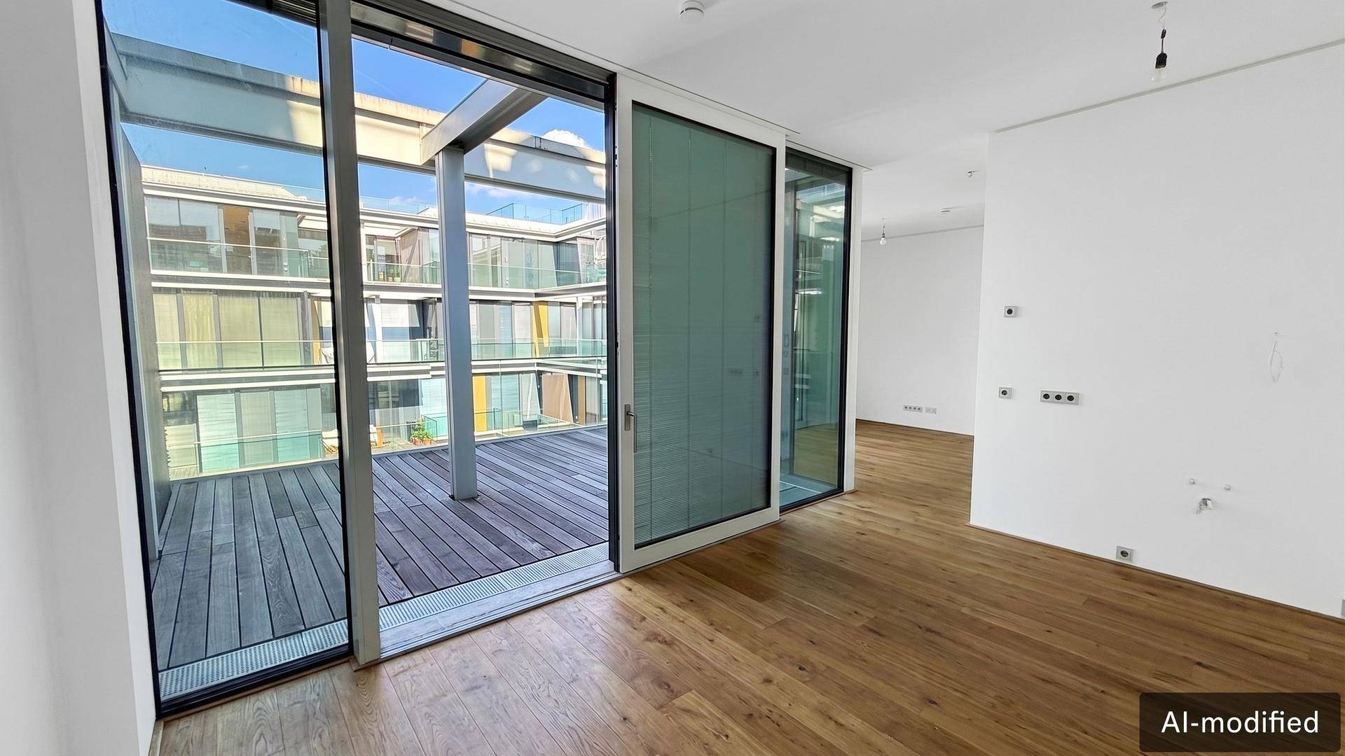 Heller Wohnraum mit Holzboden und Zugang zu einer Terrasse mit Blick auf den Innenhof.