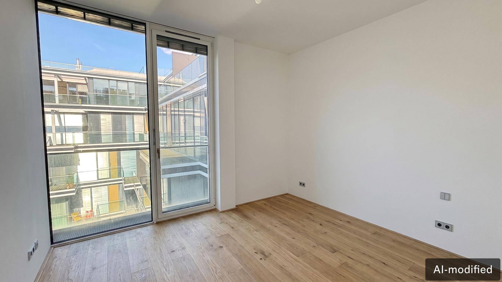 Helles Schlafzimmer mit Holzboden und großen Fenstern mit Blick auf die moderne Architektur.