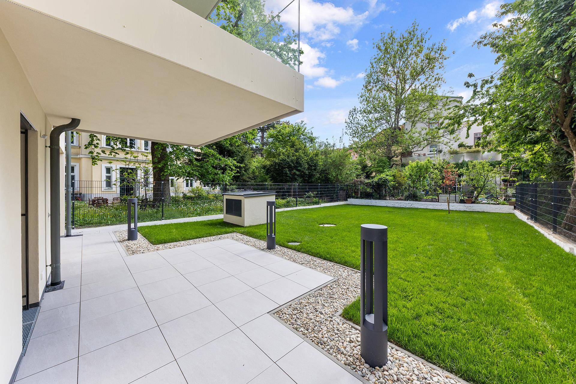Gepflasterte Terrasse mit Kiesbeet und Rasenfläche, ideal für entspannte Stunden im Freien.