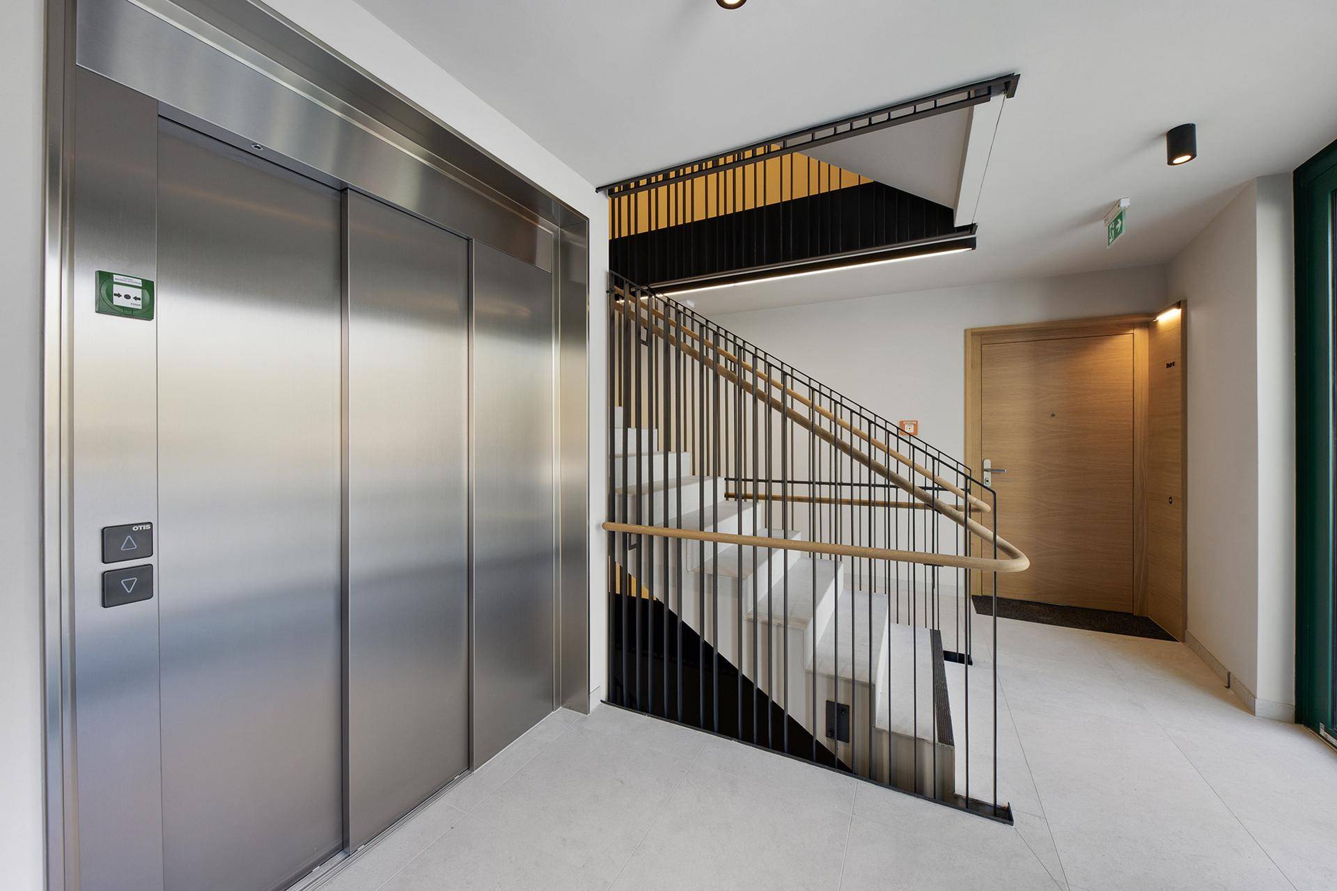 Moderner Eingangsbereich mit Aufzug und Treppenhaus in zeitgemäßem Design.