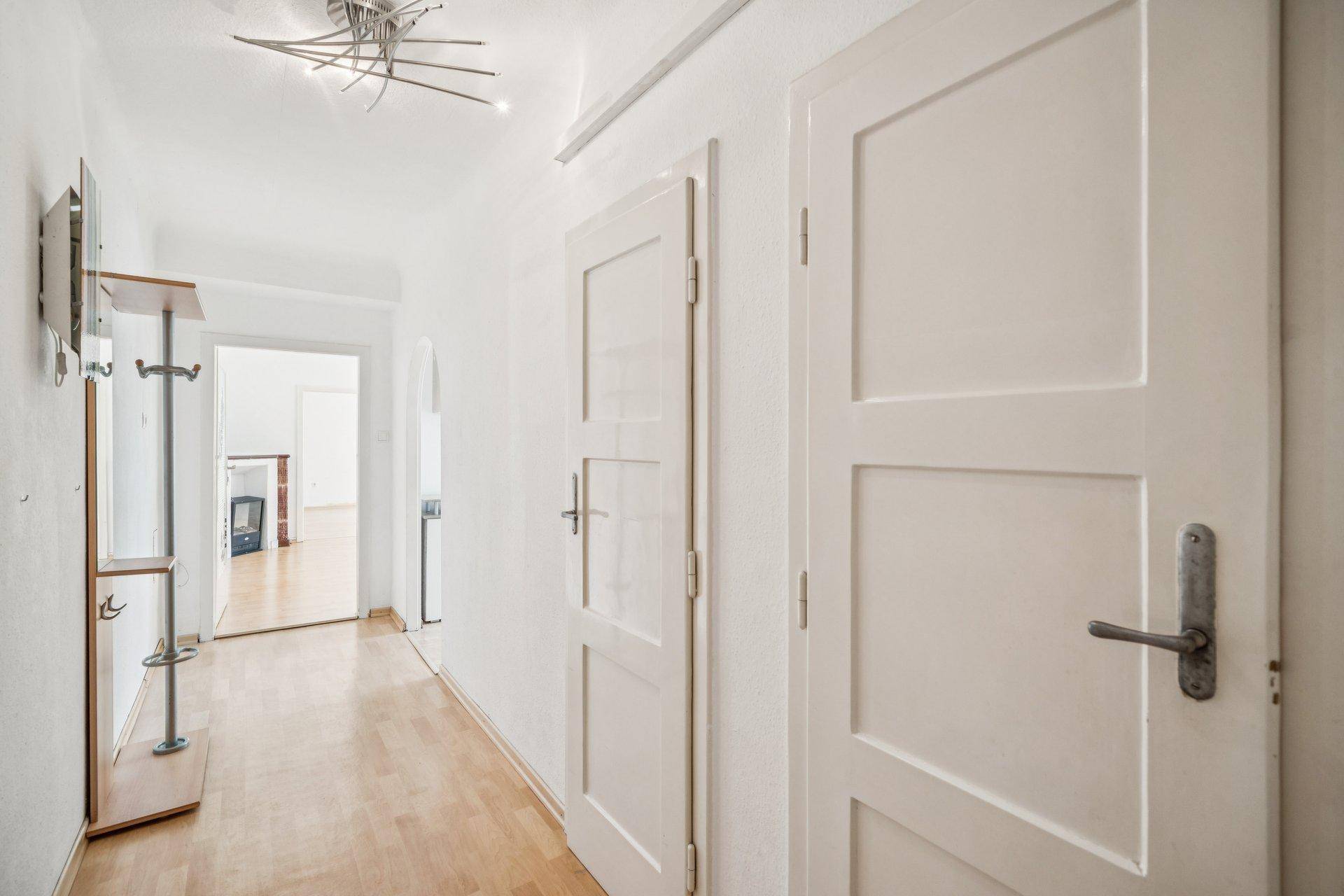 Heller Flur mit Holzboden und Zugang zu weiteren Zimmern der Wohnung.