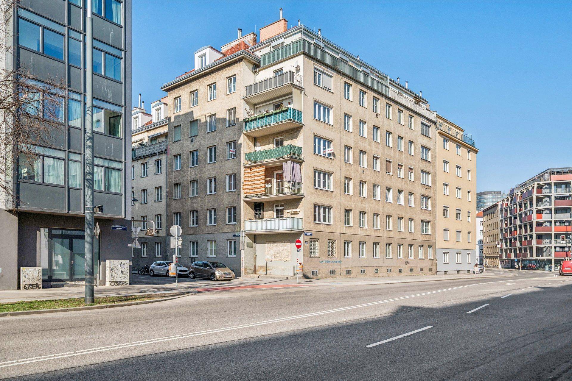 Mehrstöckiges Wohngebäude mit mehreren Balkonen an einer städtischen Straße.