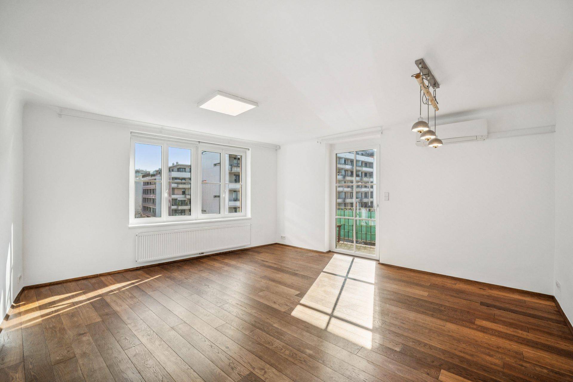 Geräumiges, leeres Wohn- und Esszimmer mit Holzboden und viel Tageslicht.