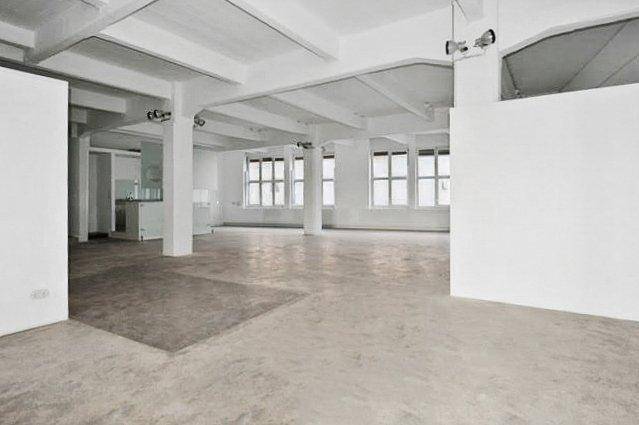 Großzügiger, leerer Loftbereich mit vielen Fenstern, hohen Decken und offenem Grundriss.
