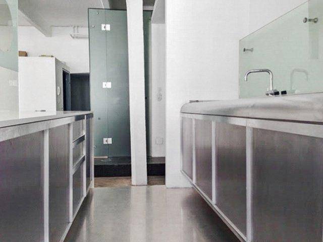 Detailansicht der Küchenzeile mit Spüle, Arbeitsfläche und moderner Glasabtrennung.