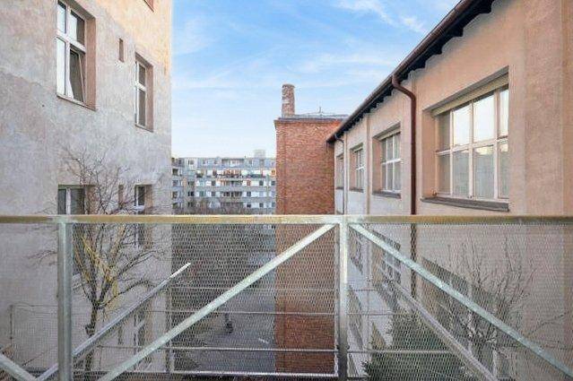 Blick von einem Balkon auf einen Innenhof zwischen Gebäuden mit städtischer Umgebung.