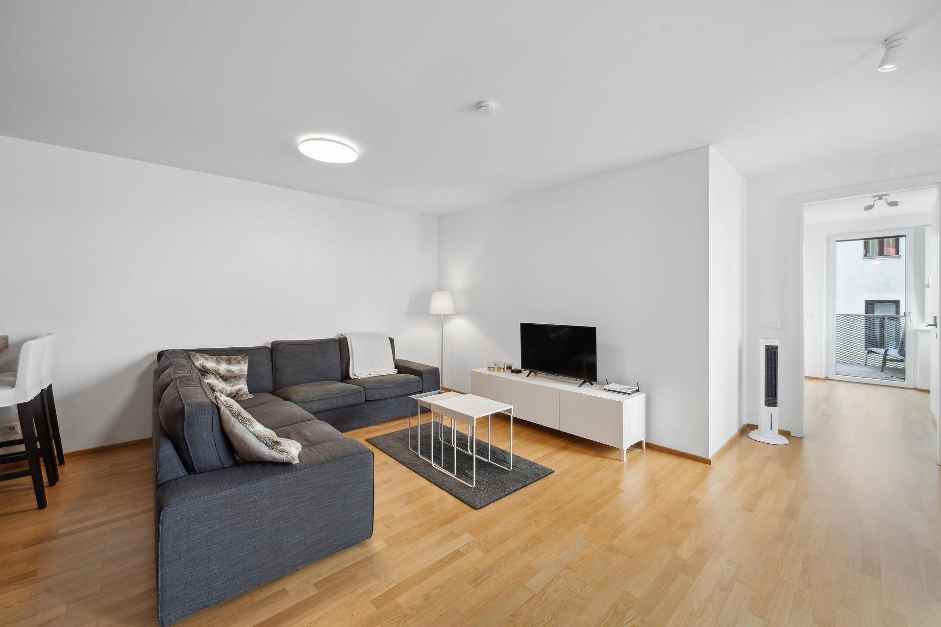 Geräumiges Wohnzimmer mit Holzboden, bequemer Sitzecke und hellem Ambiente.