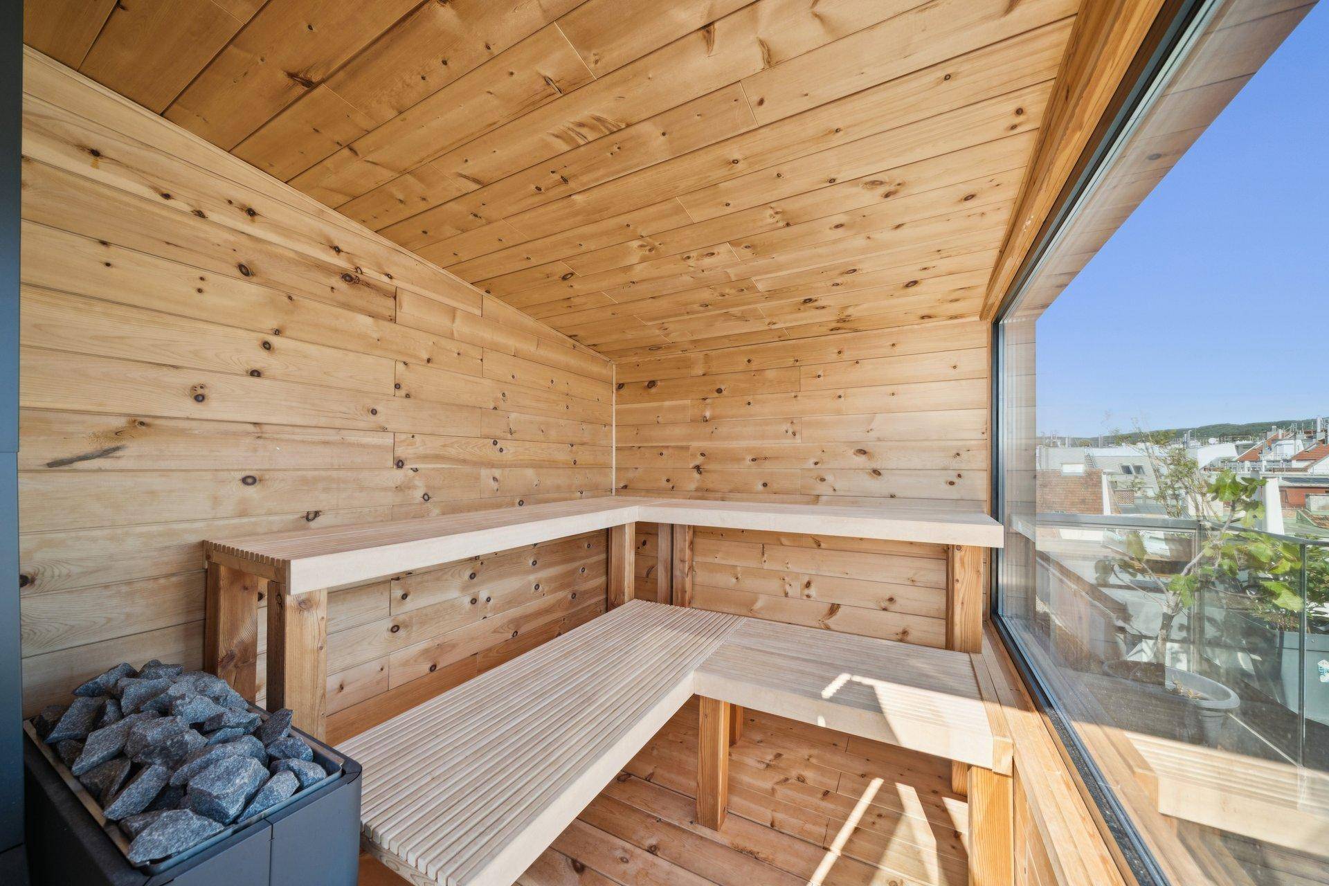 Helle Sauna mit Holzverkleidung, Sitzbänken und Panoramablick durch große Fenster.