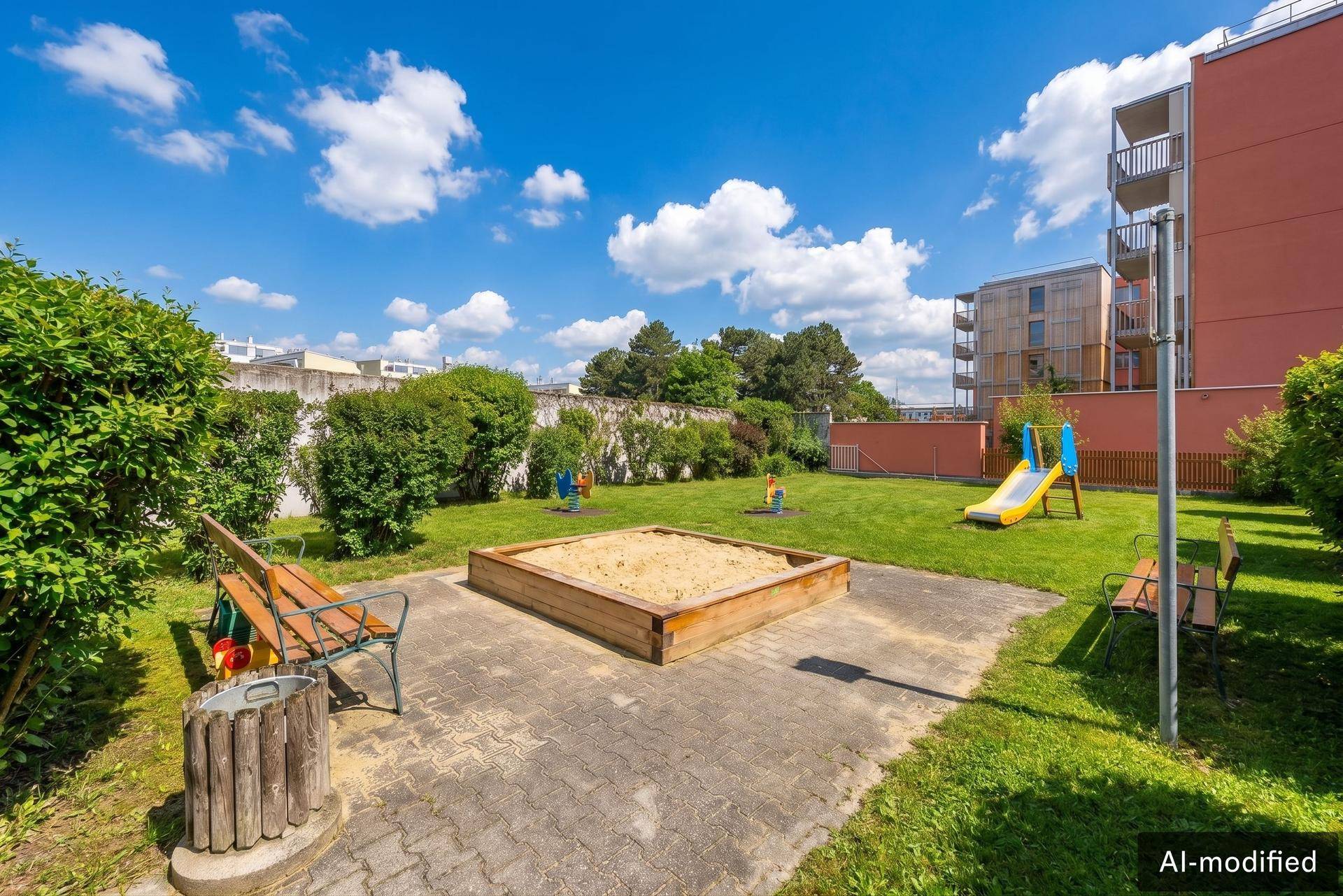 Gemeinschaftlicher Gartenbereich mit Sandkasten, Rutsche und Sitzbänken, ideal für Familien und Kinder.