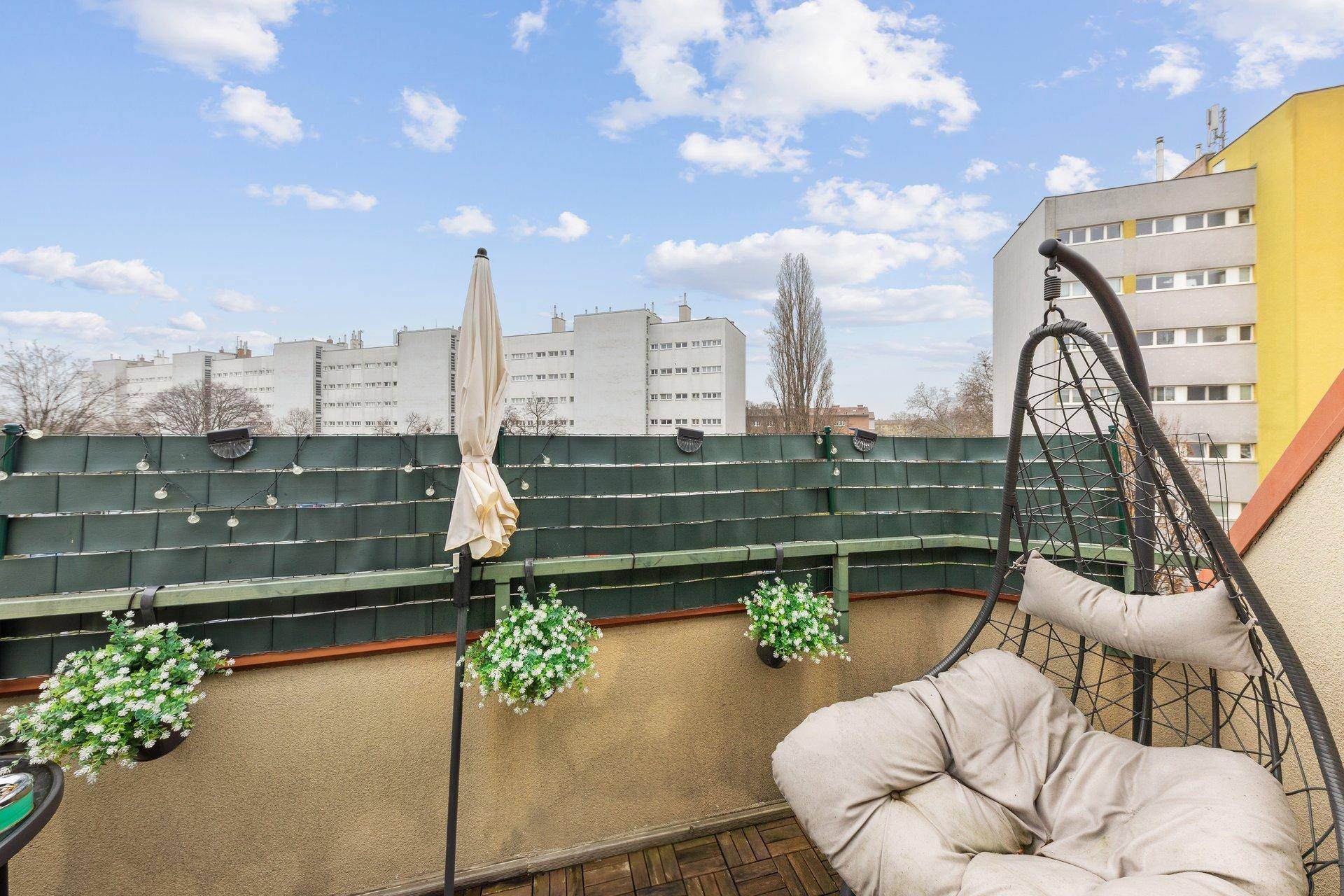 Gemütlicher Balkon mit Hängesessel und Pflanzen, ideal zum Entspannen im Freien mit Stadtblick.