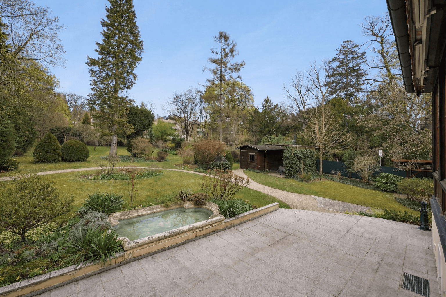 Großer, gepflegter Garten mit Terrasse, Teich und altem Baumbestand, eine grüne Oase.