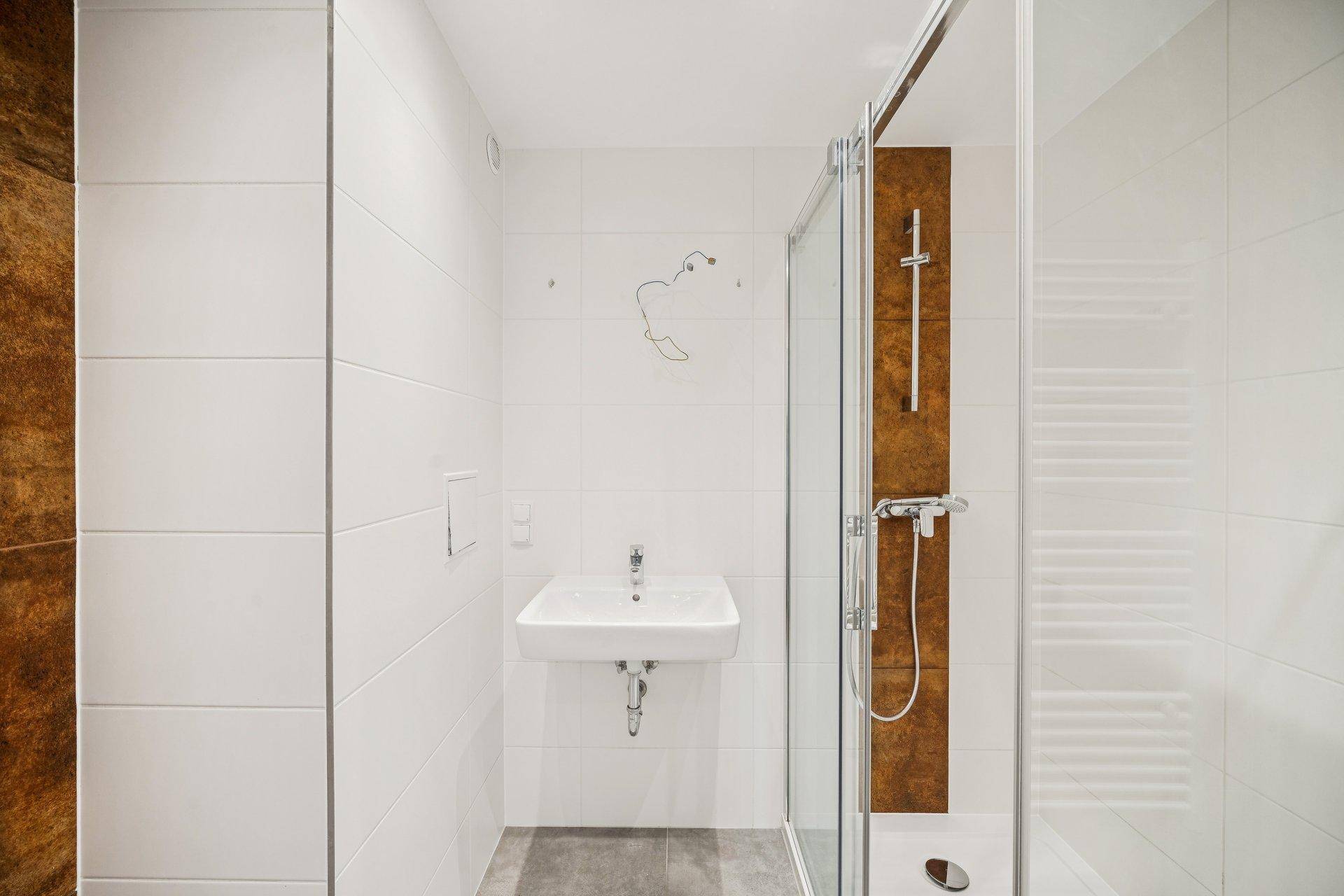 Helles Badezimmer mit weißen Fliesen, ebenerdiger Dusche und modernem Waschbecken.