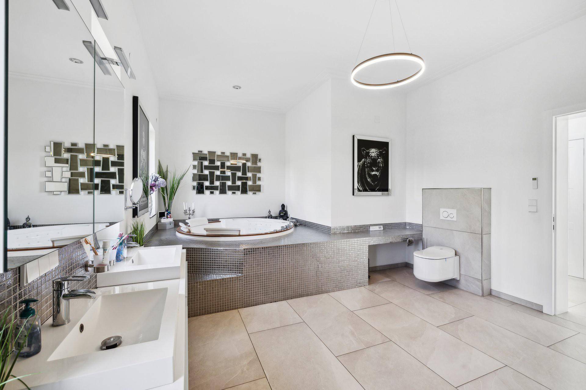 Großes, modernes Badezimmer mit Doppelwaschbecken, eingelassener Badewanne und Wand-WC.