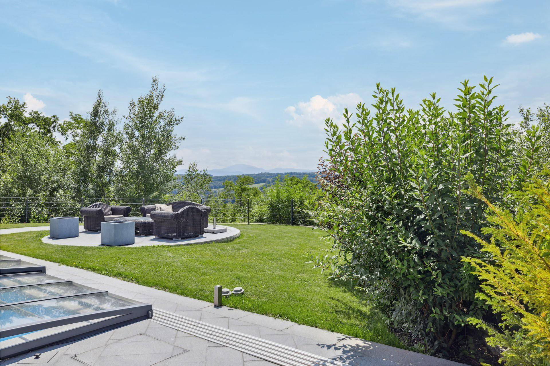 Gepflegter Garten mit gemütlicher Lounge-Ecke und Panoramablick auf die umliegende Hügellandschaft.