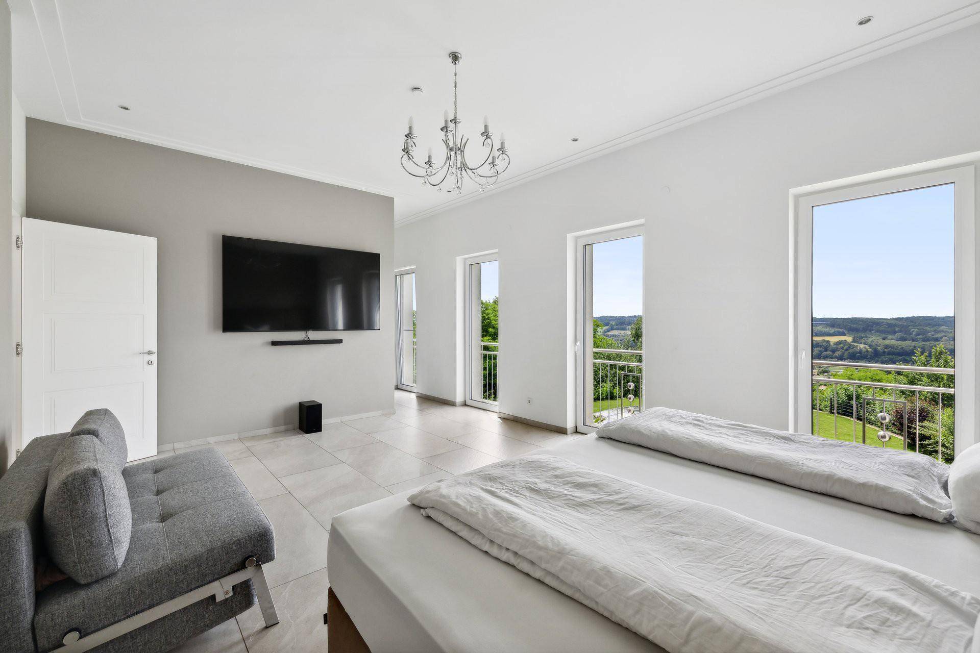 Geräumiges Schlafzimmer mit großem Bett, Flachbildfernseher und Zugang zu französischen Balkonen.