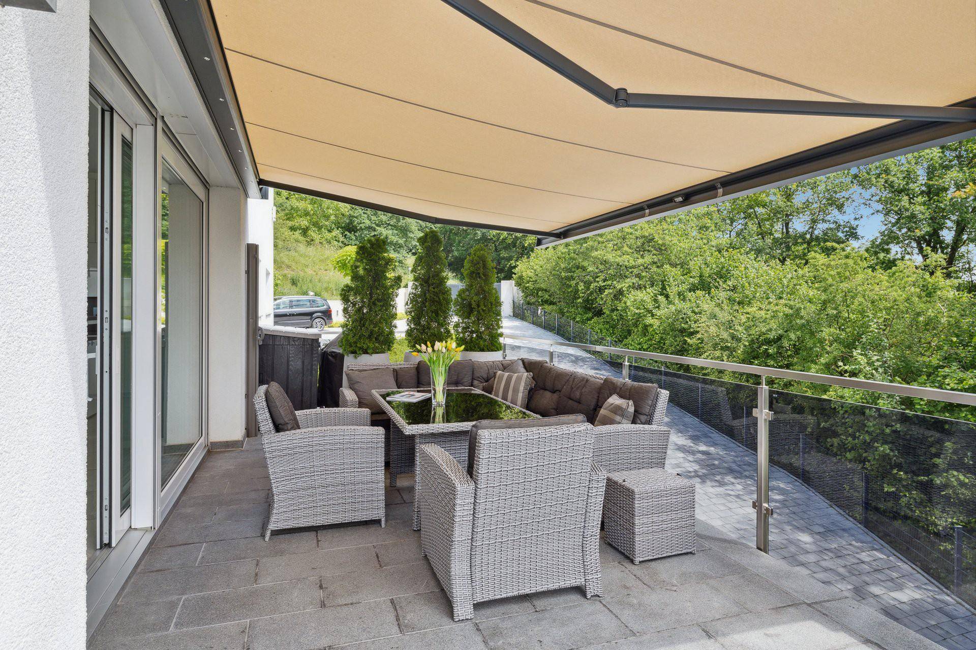 Überdachte Terrasse mit bequemen Lounge-Möbeln und Markise, ideal für entspannte Stunden im Freien.