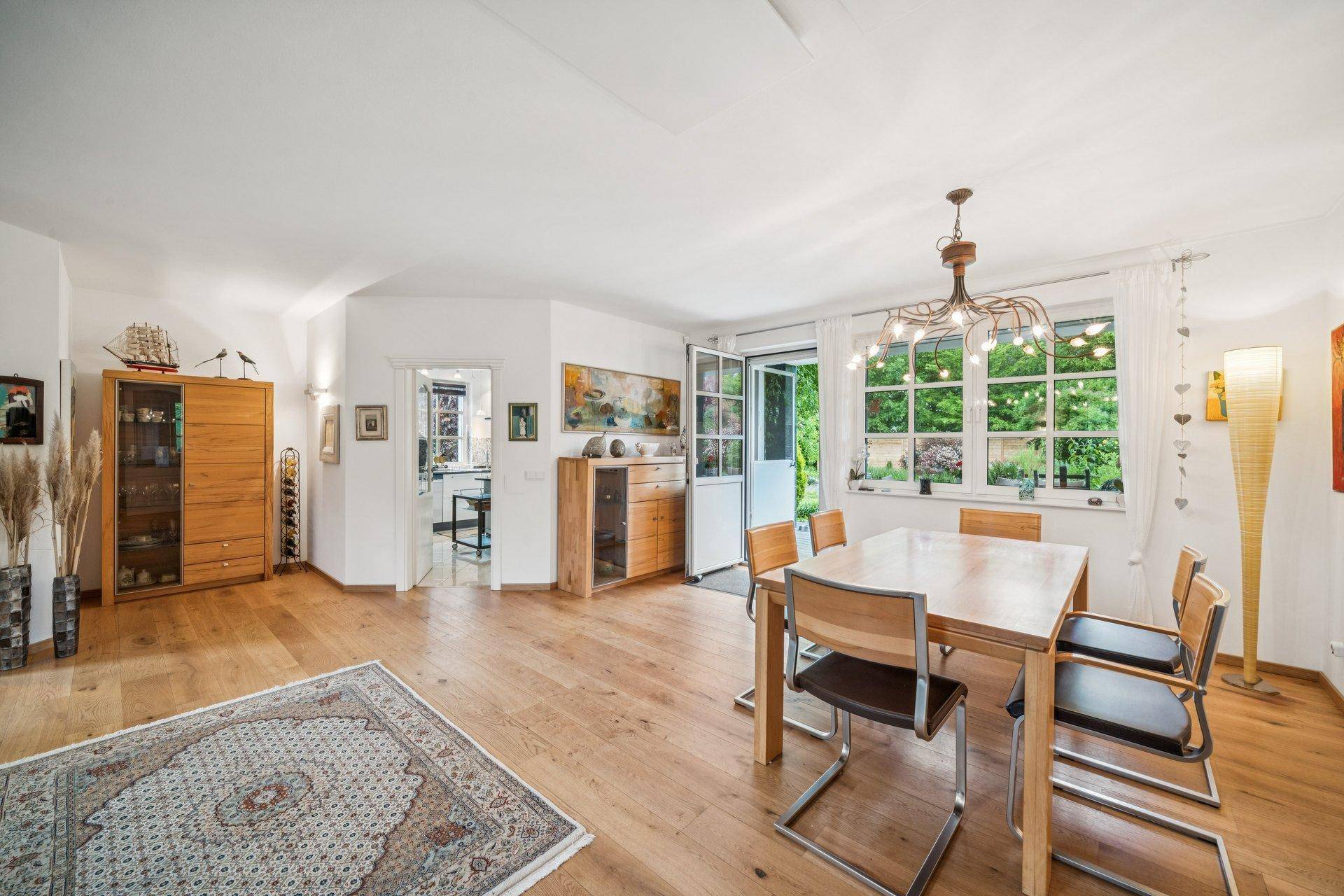 Heller Essbereich mit Holztisch, Stühlen und Zugang zum Garten durch große Fenstertüren.