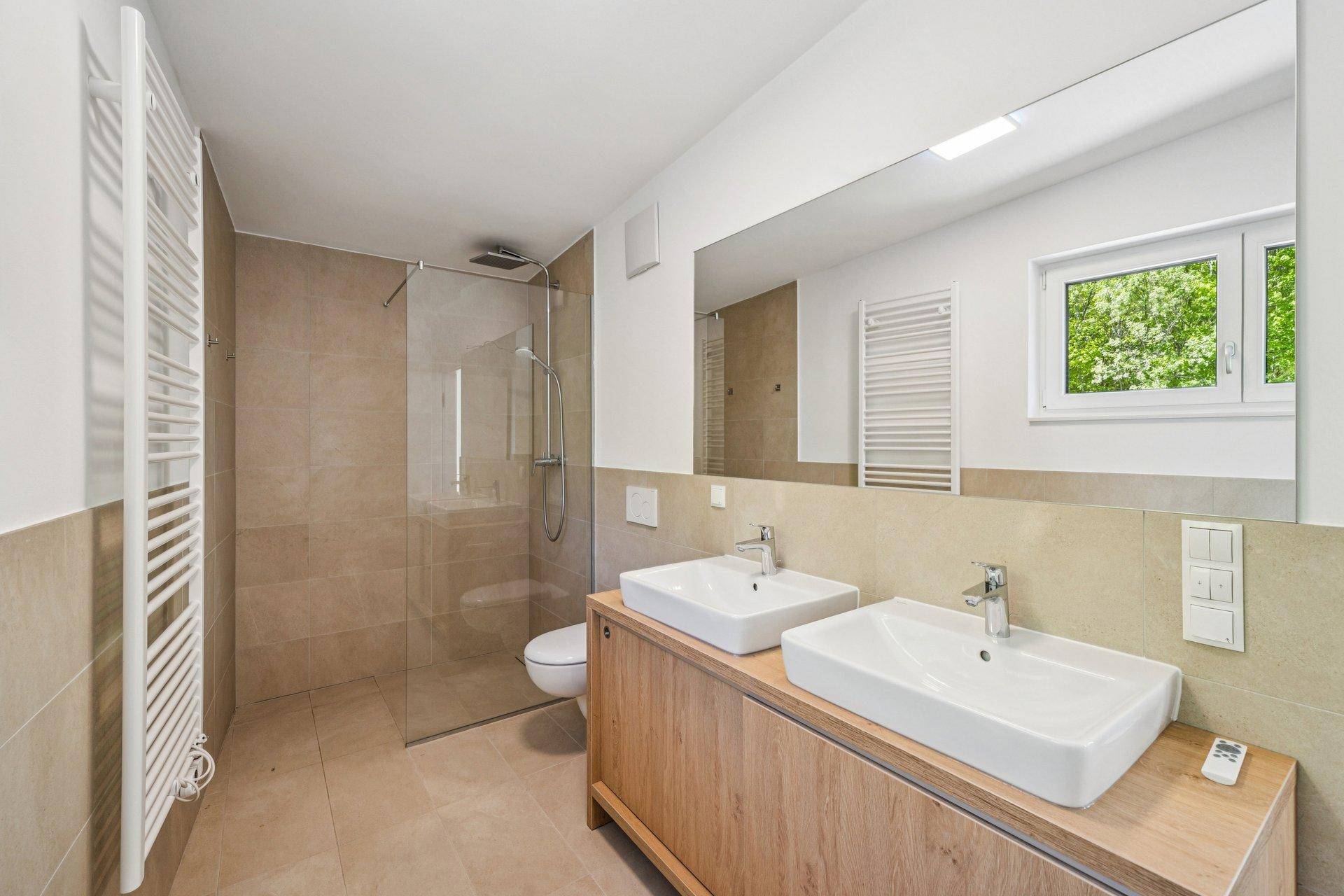 Modernes Badezimmer mit Doppelwaschbecken, ebenerdiger Dusche und beheiztem Handtuchhalter.