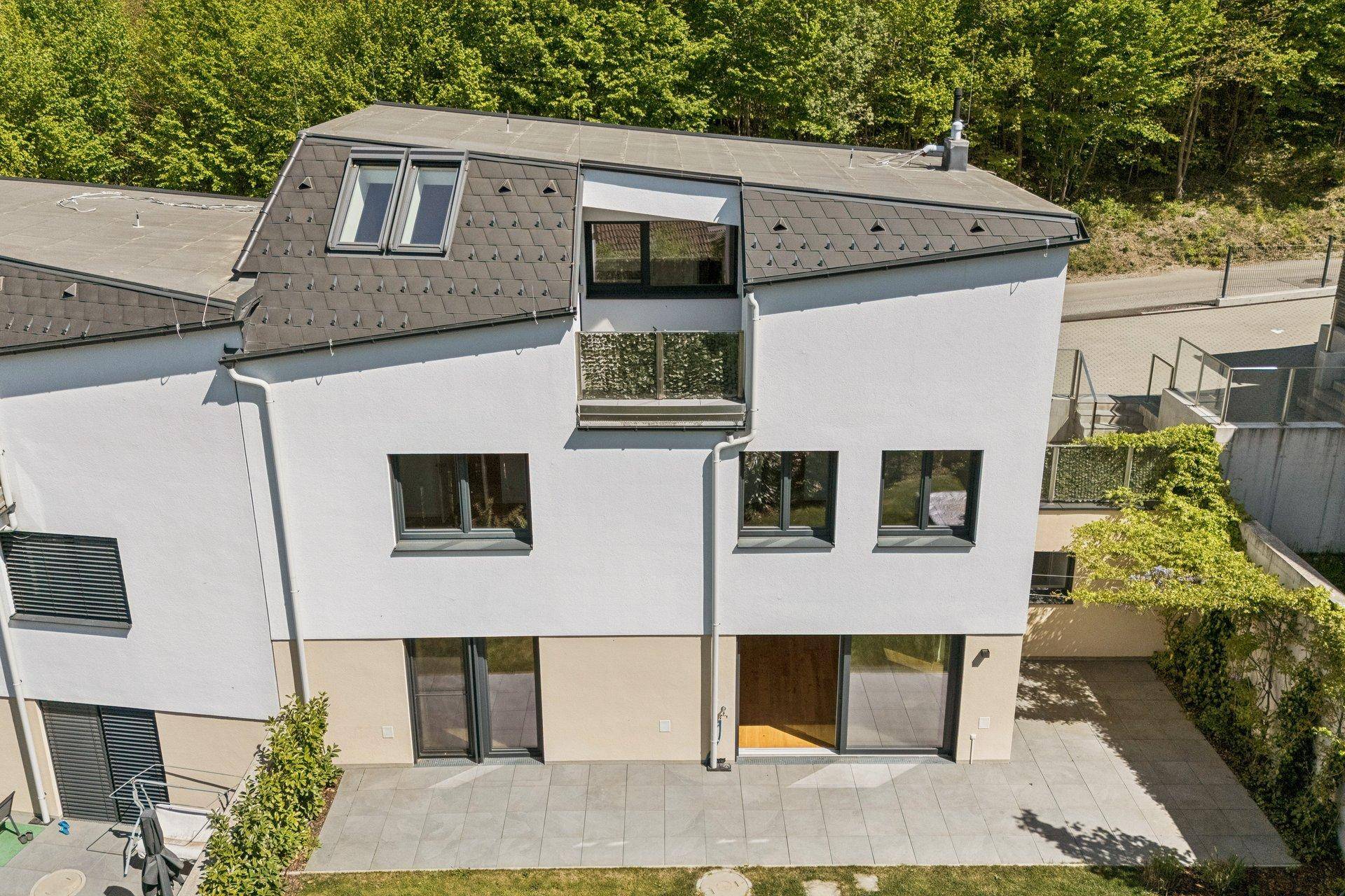 Ansicht der modernen Gebäudefassade mit Terrassen, Balkonen und einem markanten Dach mit Dachfenstern.