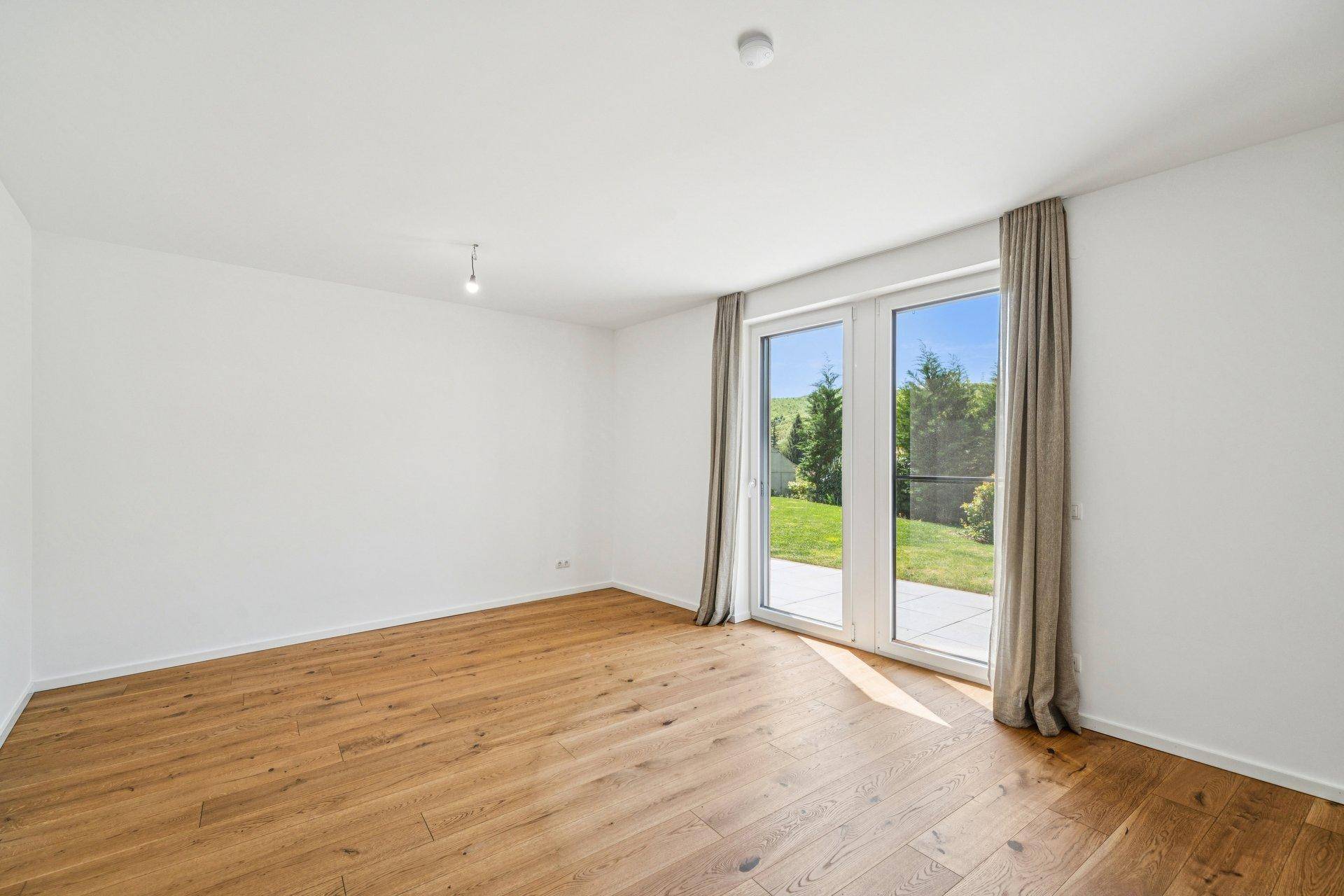 Helles Zimmer mit Holzboden und Zugang zur Terrasse, ideal als Schlaf- oder Arbeitszimmer.