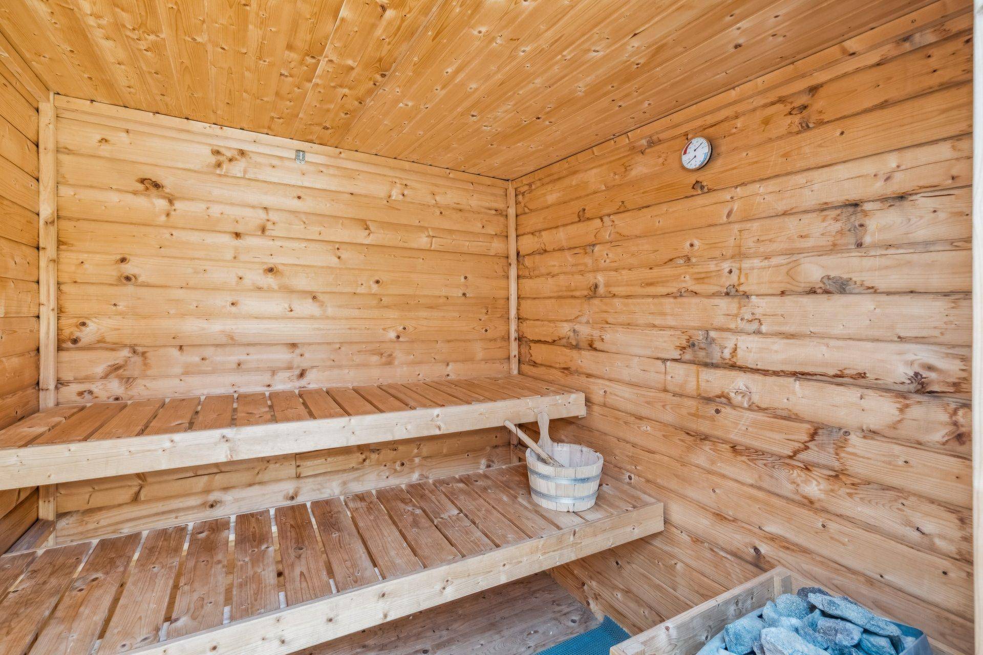 Innenansicht einer Holzsauna mit Bänken und Saunaofen für Entspannung.