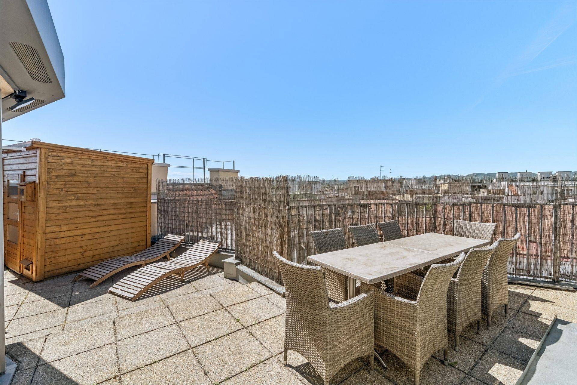 Große Dachterrasse mit Essbereich, Sonnenliegen und Panoramablick über die Stadt.