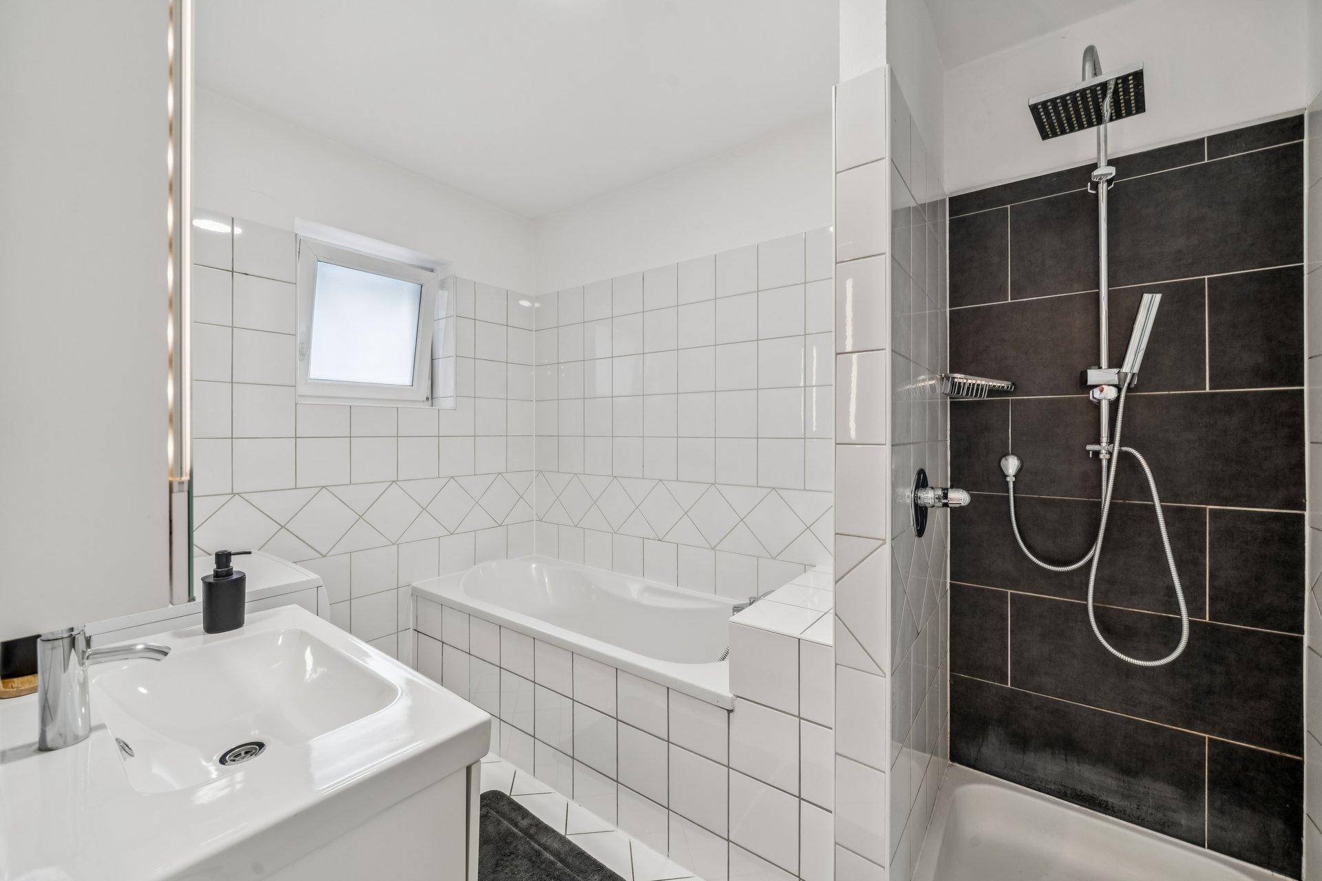 Modernes Badezimmer mit Badewanne, separater Dusche und weißen Fliesen.
