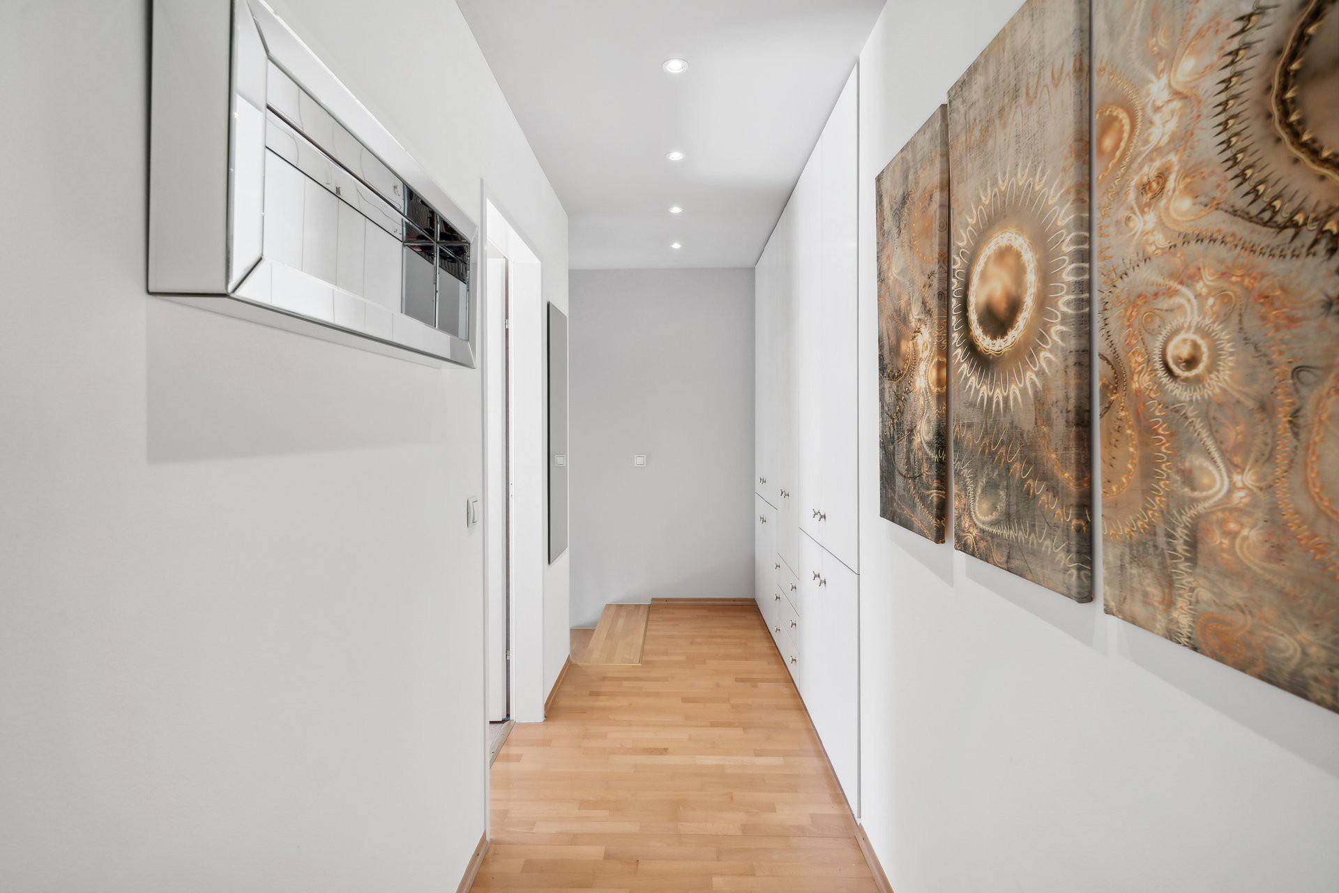 Heller Flur mit Holzboden, Einbauschränken und moderner Dekoration.