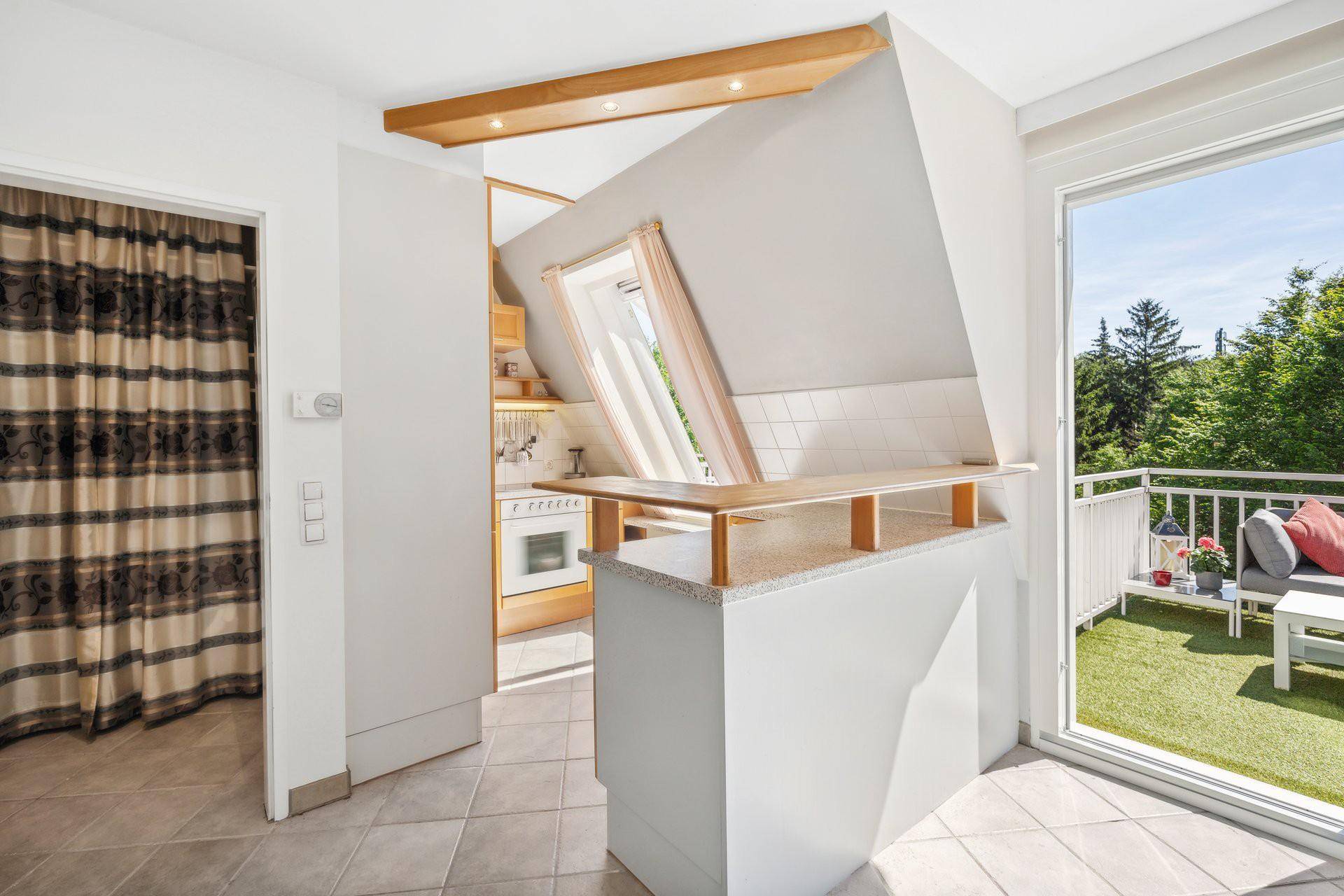 Offene Küche mit Bar und Zugang zu einem sonnigen Balkon.