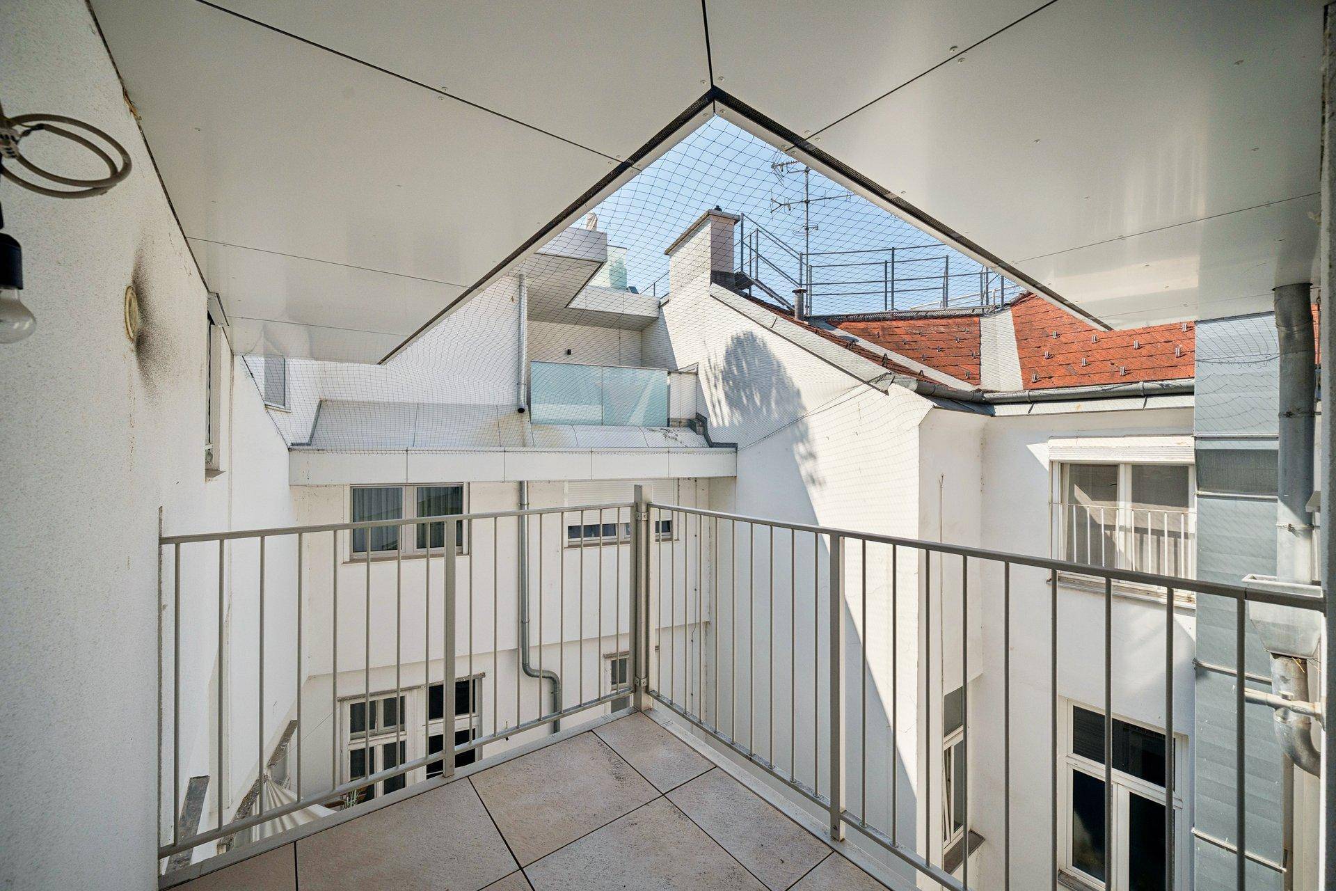 Kleiner Balkon mit Blick auf den Innenhof und die umliegenden Gebäude.