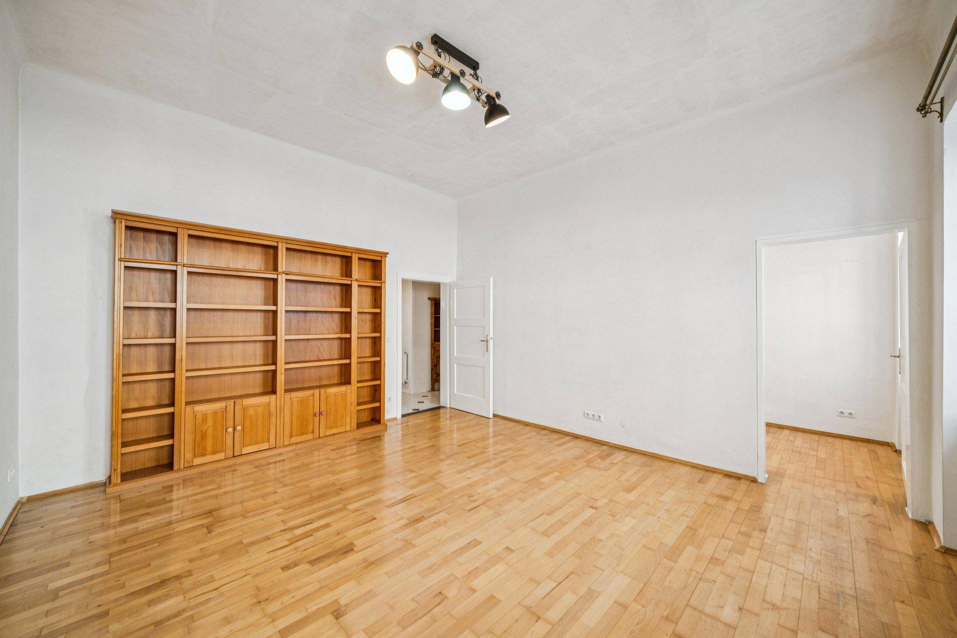 Geräumiges Zimmer mit Parkettboden und eingebautem Holzregal, ideal für Wohn- oder Arbeitsbereich.