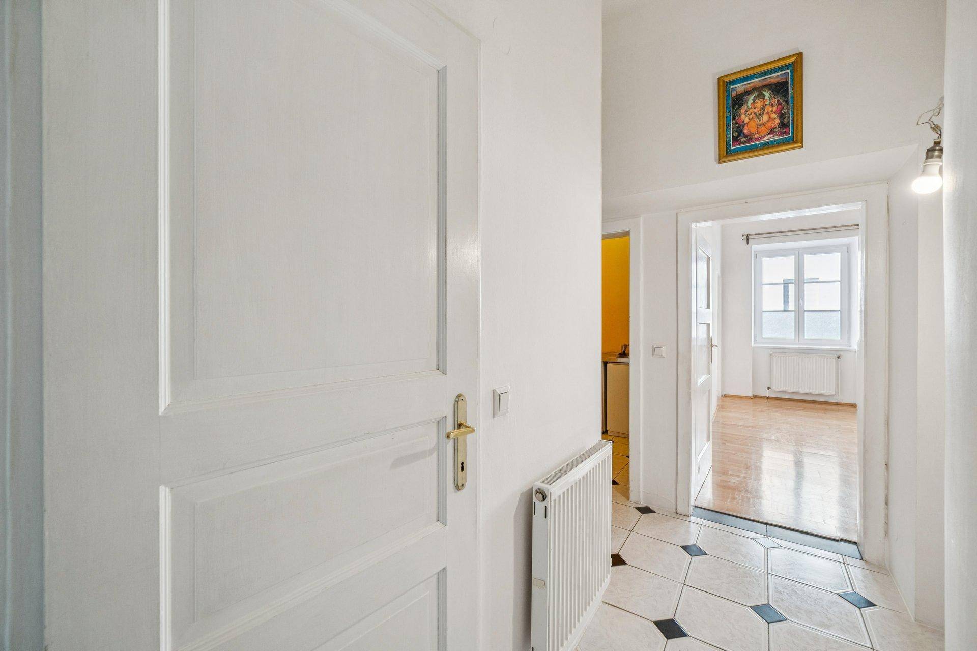 Eingangsbereich mit schwarz-weißem Fliesenboden und Blick in angrenzende Zimmer.