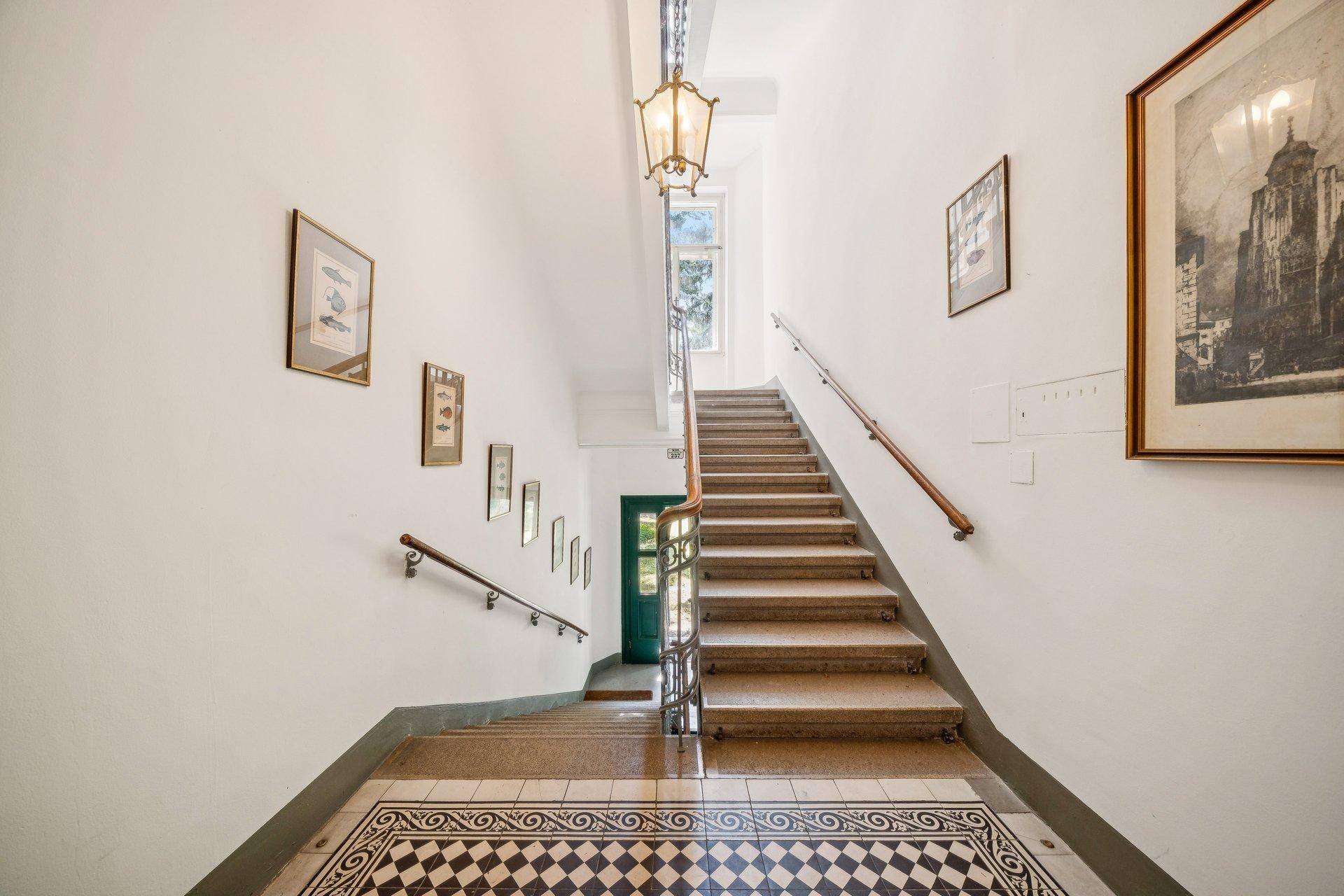Großzügiges Treppenhaus mit historischem Charme, Fliesenboden und natürlichem Licht.