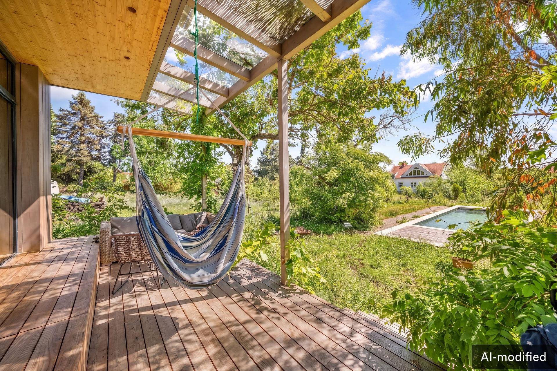 Gemütliche Holzterrasse mit Hängematte und Blick auf den Garten und Pool.