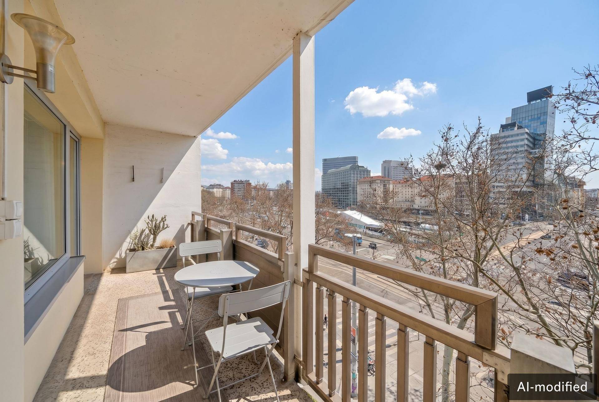 Balkon mit kleinem Tisch und Stühlen, bietet einen weiten Blick über die Stadtlandschaft.