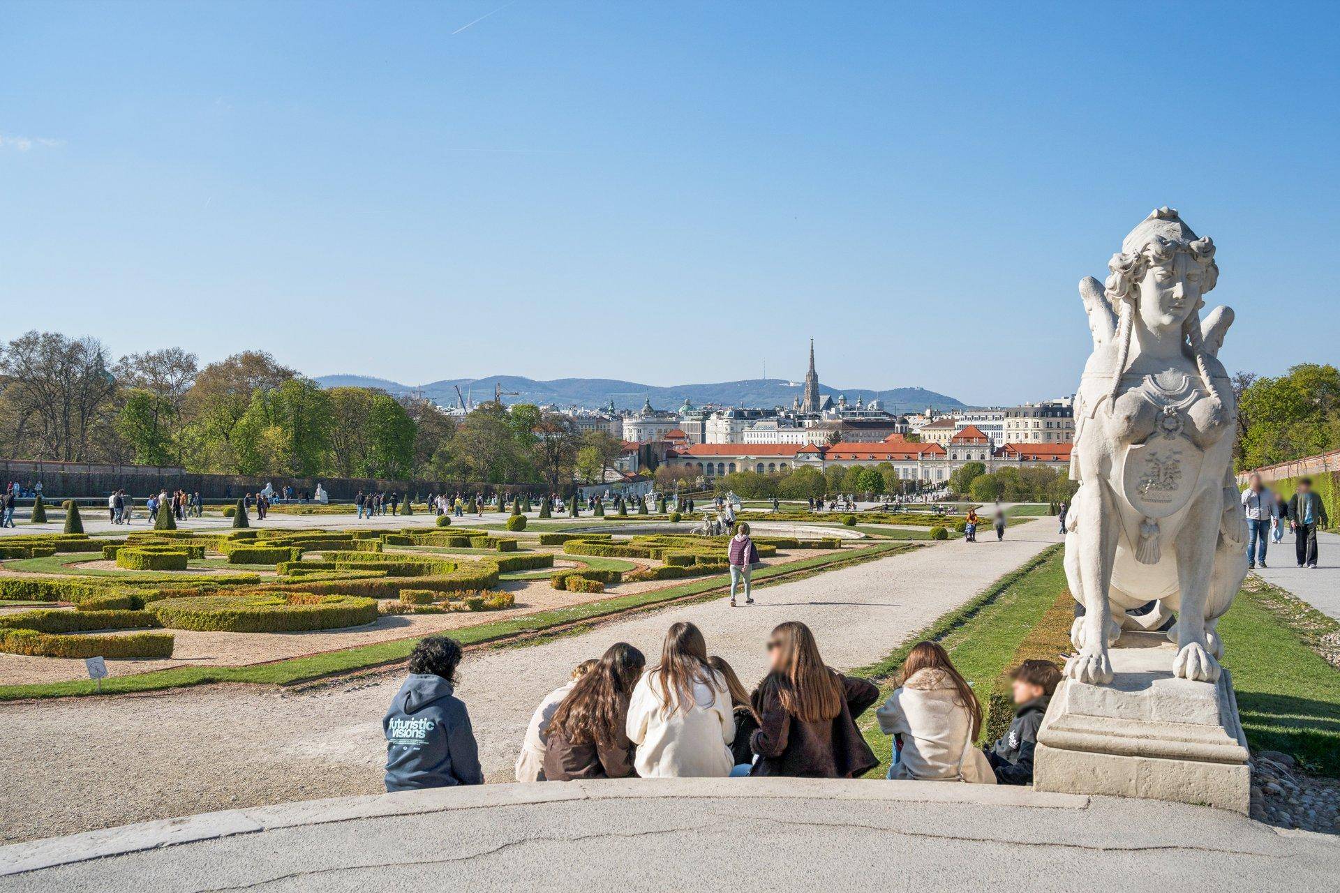 Panoramablick auf eine weitläufige Gartenanlage mit Skulpturen und der Stadt im Hintergrund.