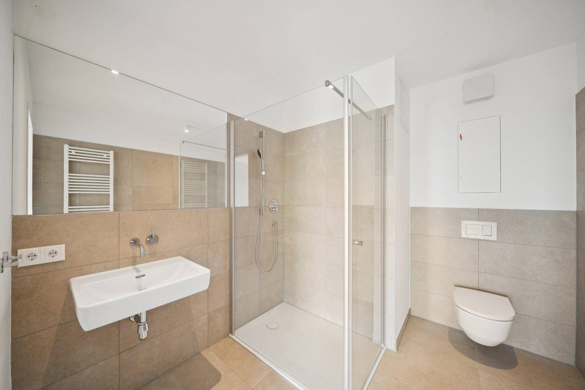 Helles Badezimmer mit begehbarer Dusche, Einzelwaschbecken und beigefarbenen Fliesen.